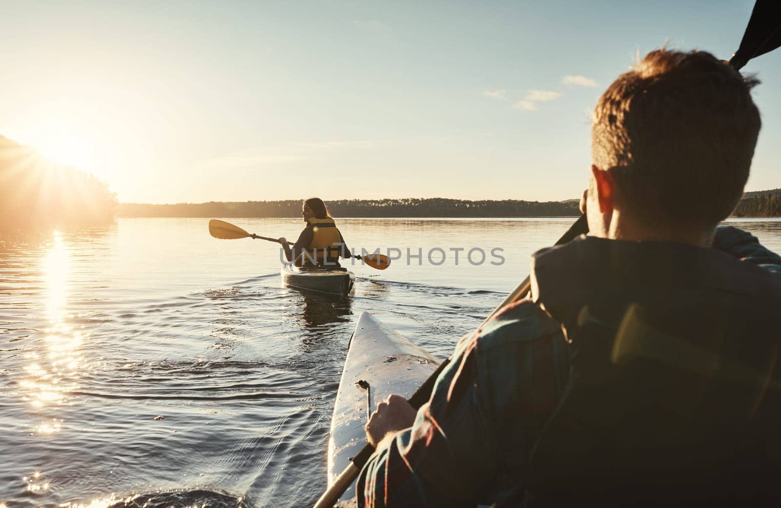 I missed kayaking with her. a young couple kayaking on a lake outdoors. by YuriArcurs