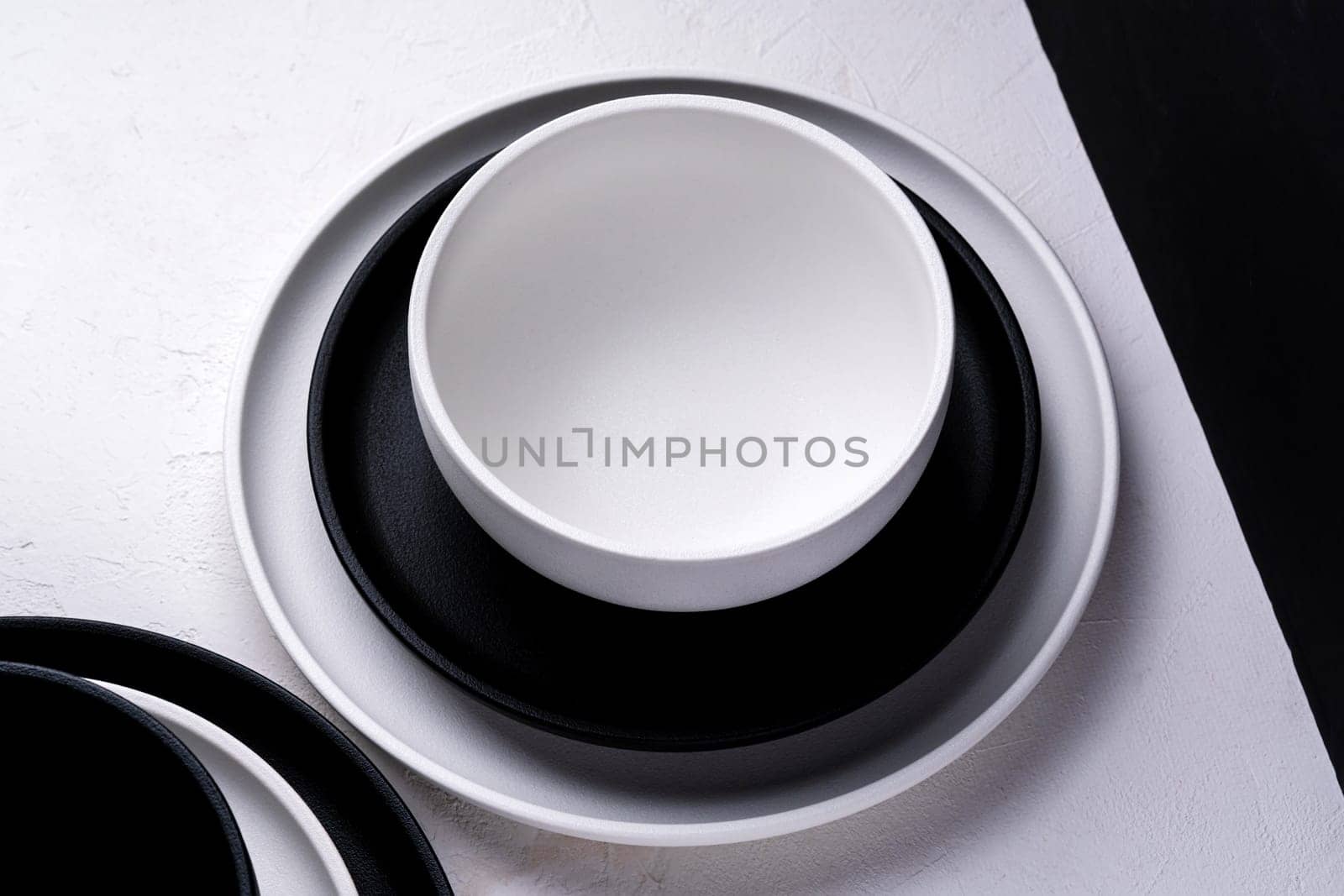 Different black and white empty plates and bowls on a white table. by darksoul72