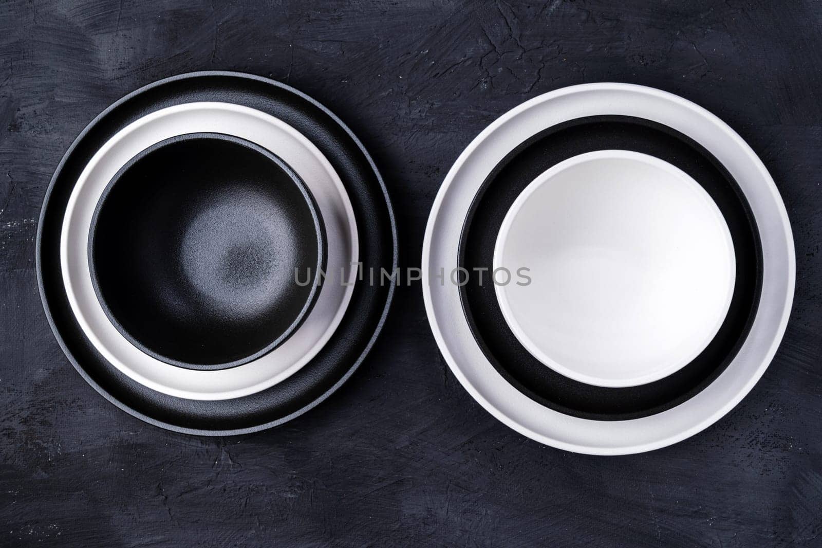 Empty ceramic plate, black and white on a concrete white background. Stylish tableware