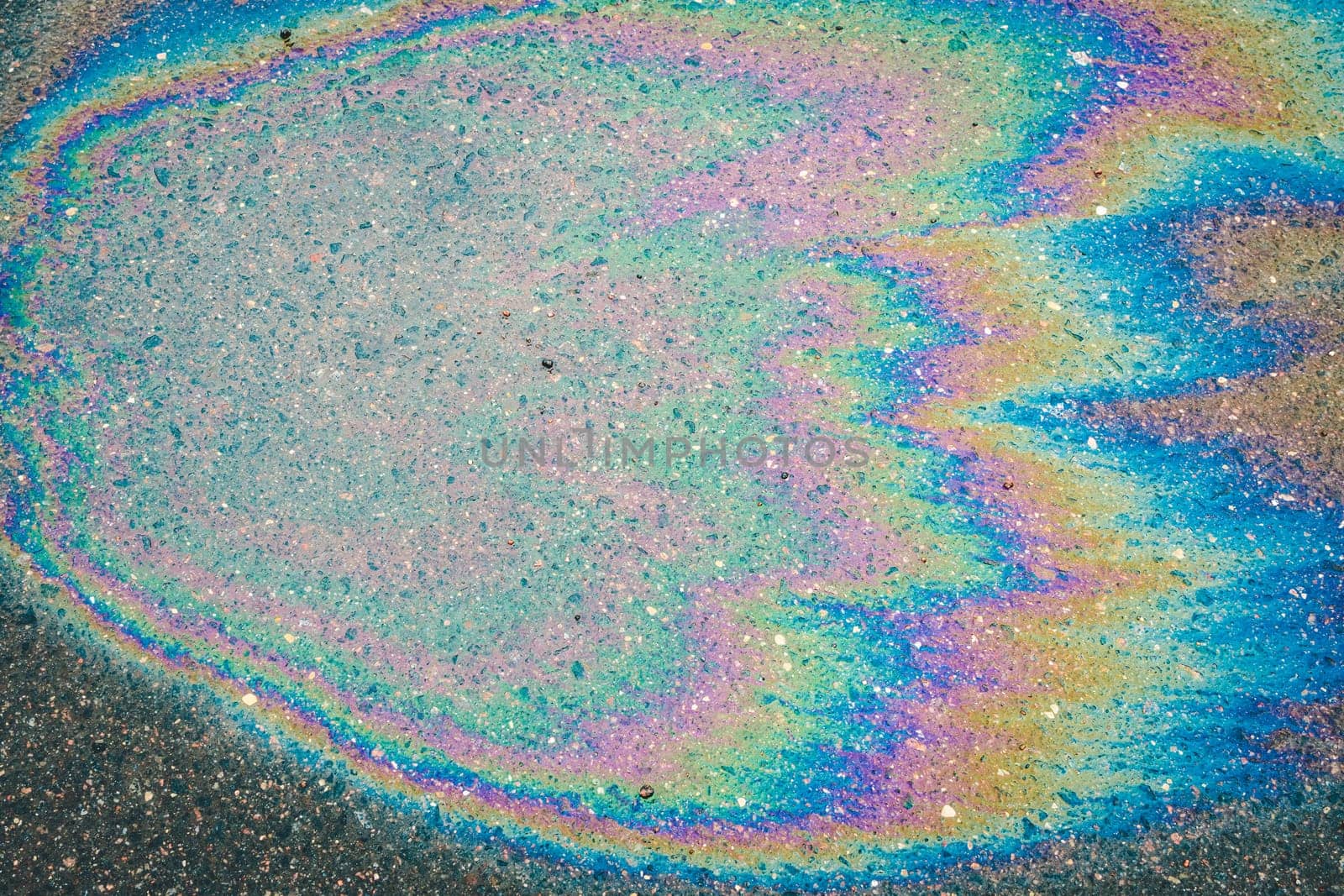 Iridescent multi-colored stain from engine oil on asphalt close-up
