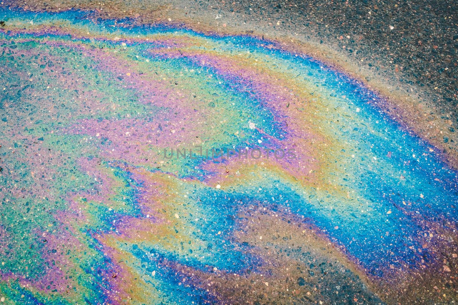 Petroleum fuel spilled on wet asphalt, abstract background.