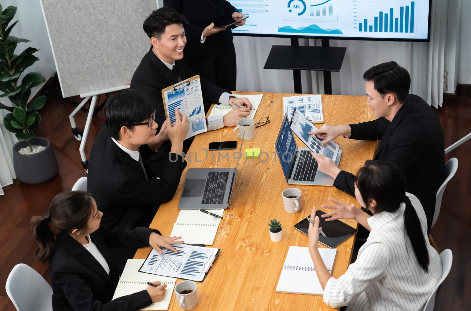 Top widen view of confidence of company presentation on financial analyzed by business intelligence in dashboard report with businesspeople in boardroom meeting to promote harmony in workplace concept
