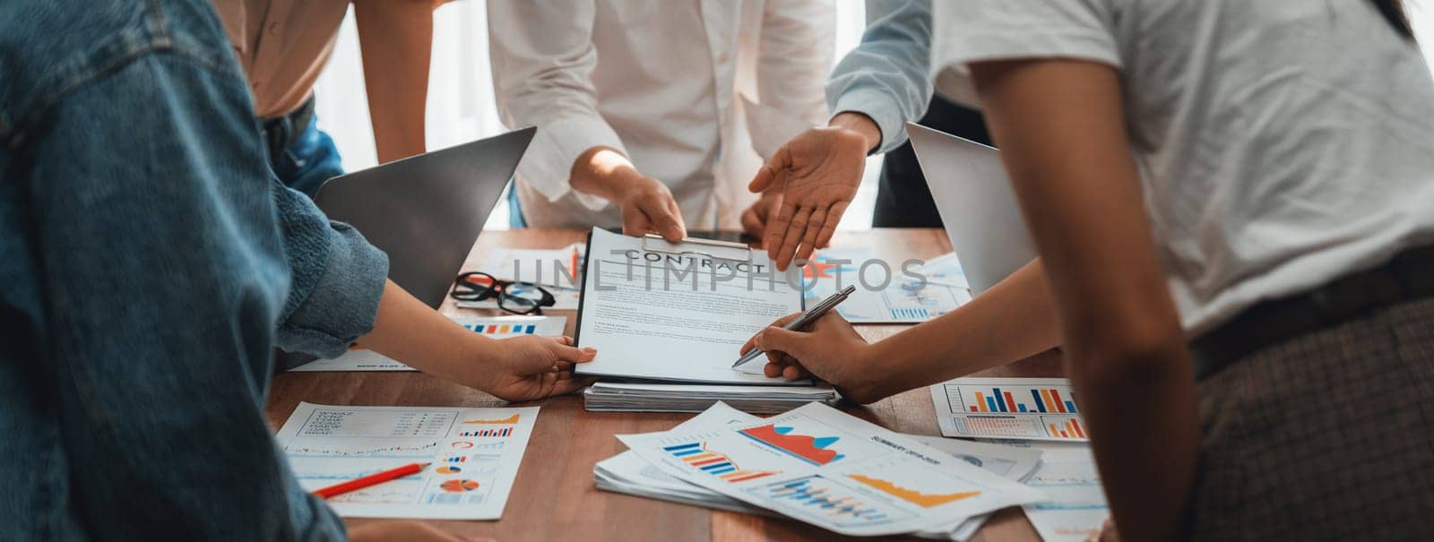 Analyst team utilizing BI Fintech to analyze and pointing at financial dashboard paper office. Businesspeople examining report paper on table for business insight. Panorama shot. Scrutinize