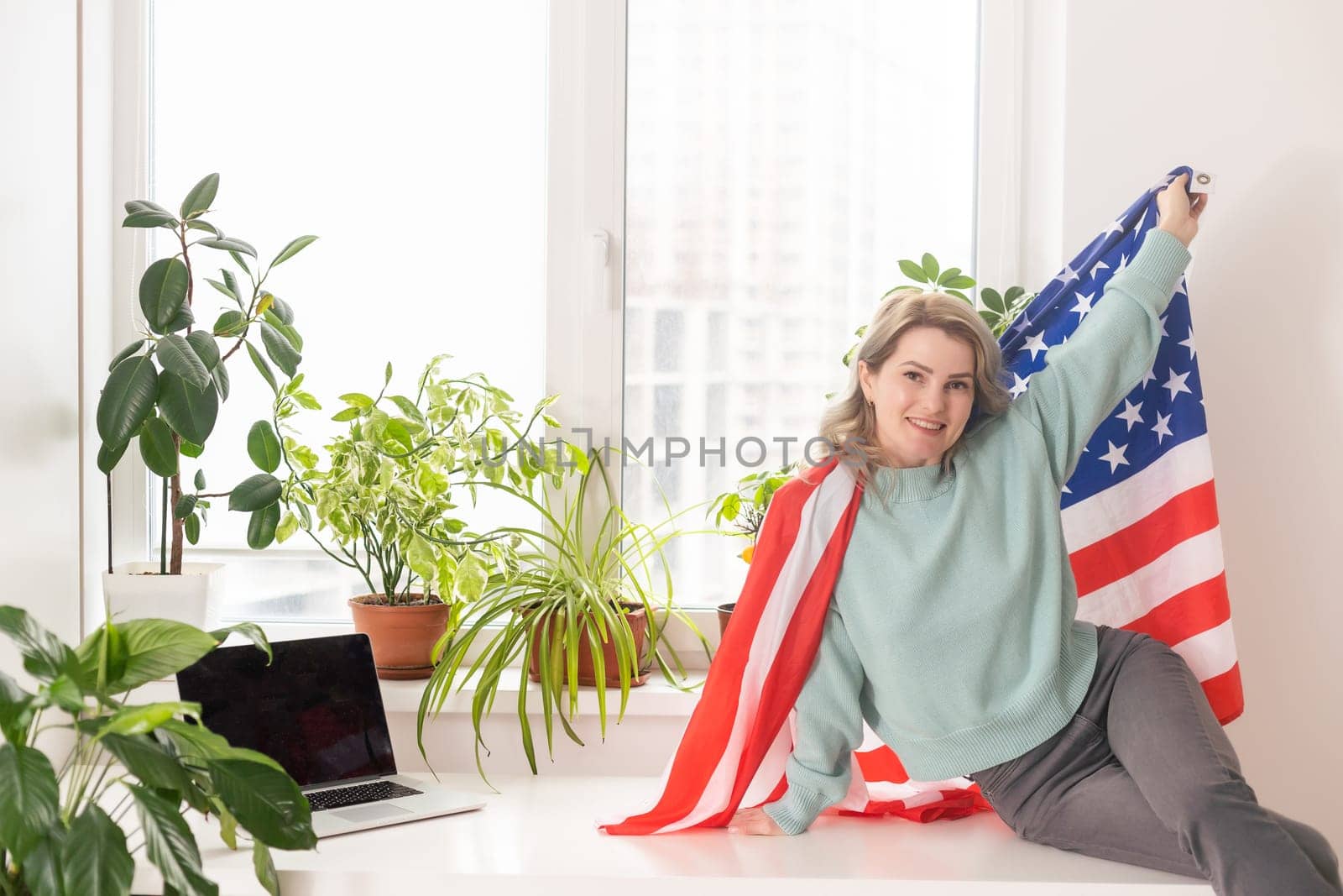 Positive teacher in headset having online lesson on laptop near flags in school.