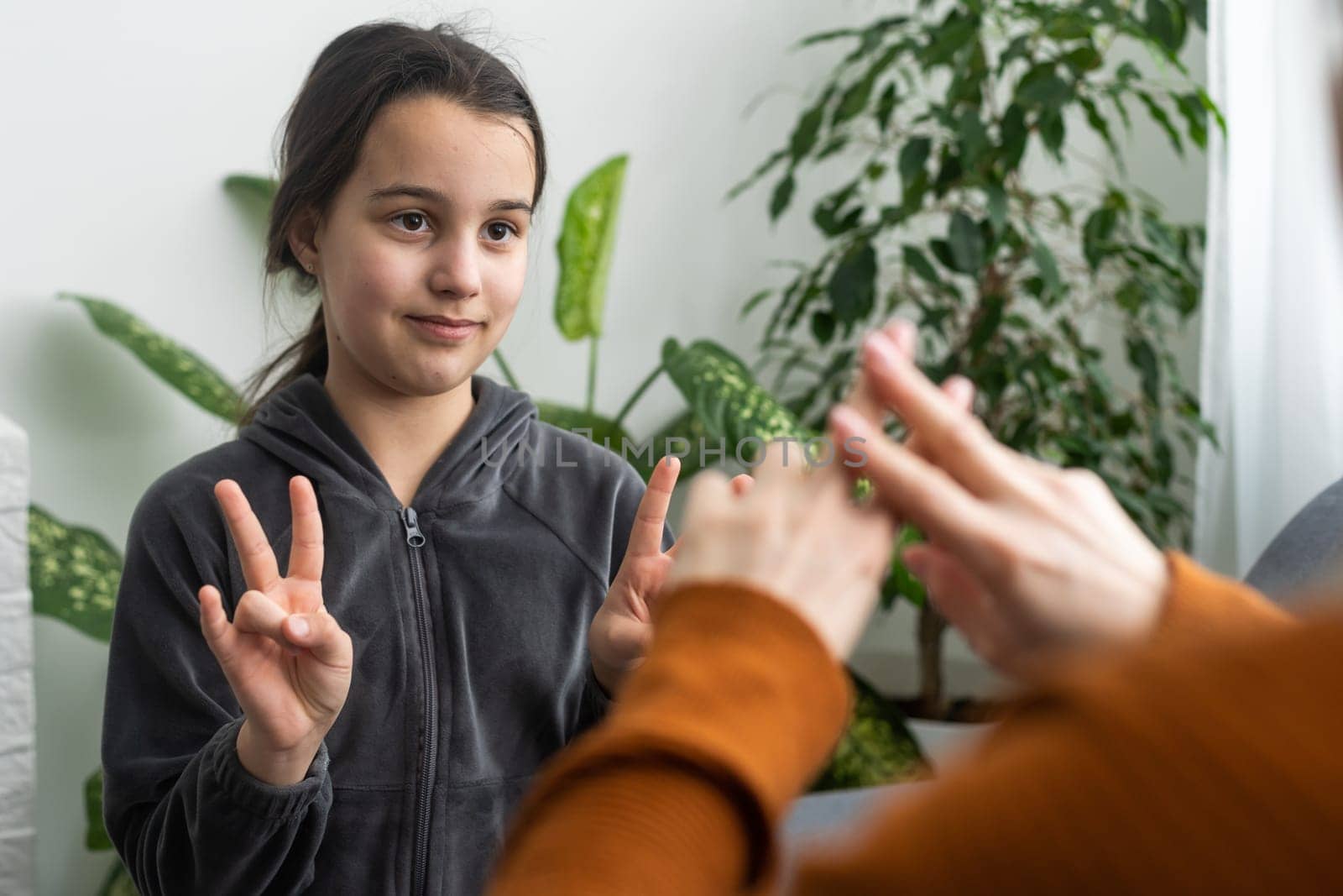 Cute little girl make hand gesture learning sign language with mom or female nanny, smiling small kid practice nonverbal talk with teacher at home, preschooler child have lesson with tutor.