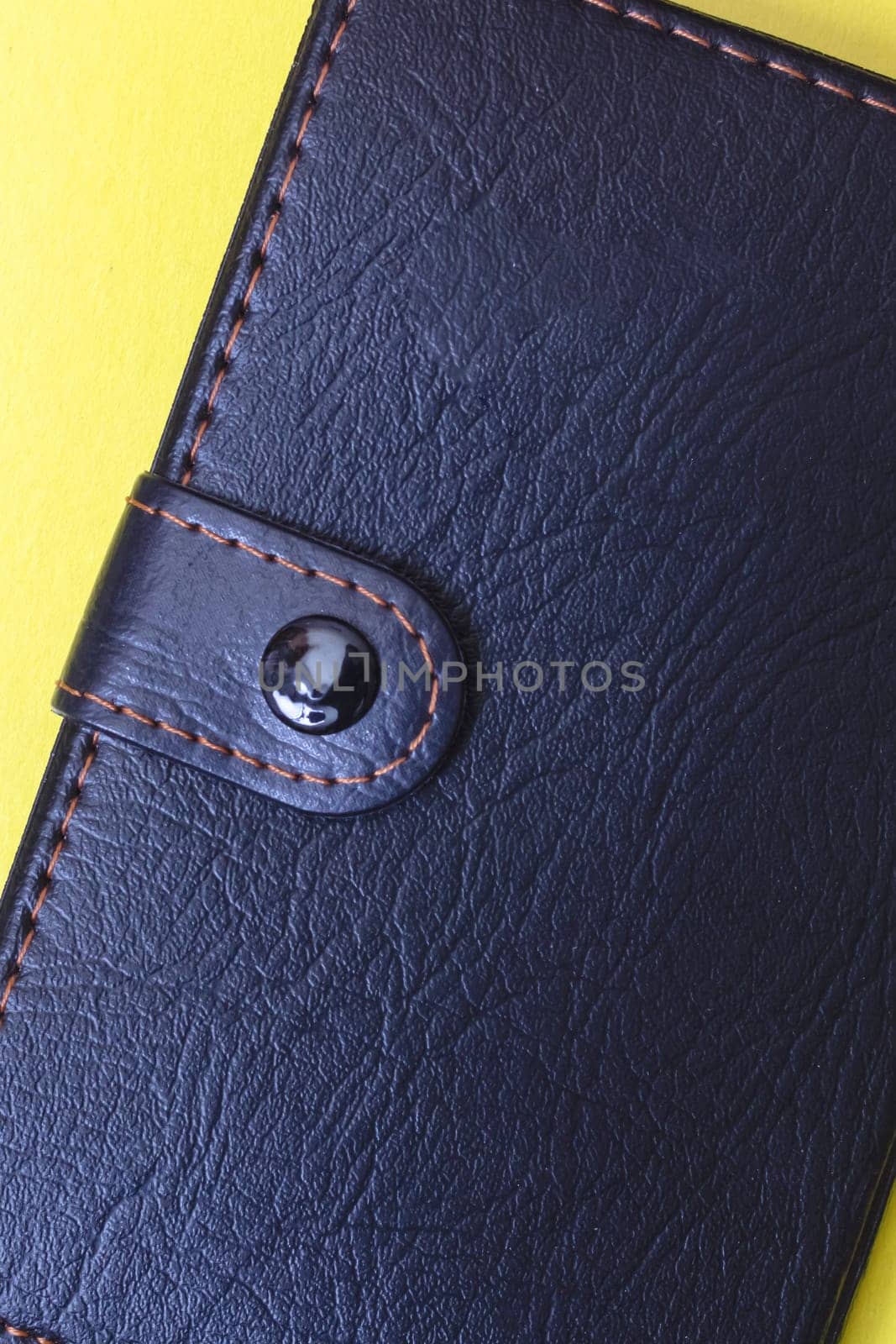 Black notebook and pen on a yellow background