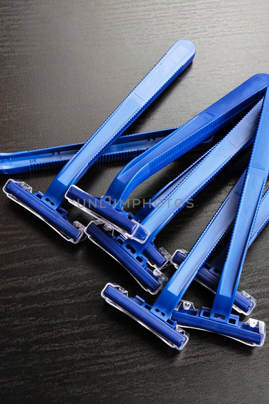 Pile of blue razors on a wooden background close up