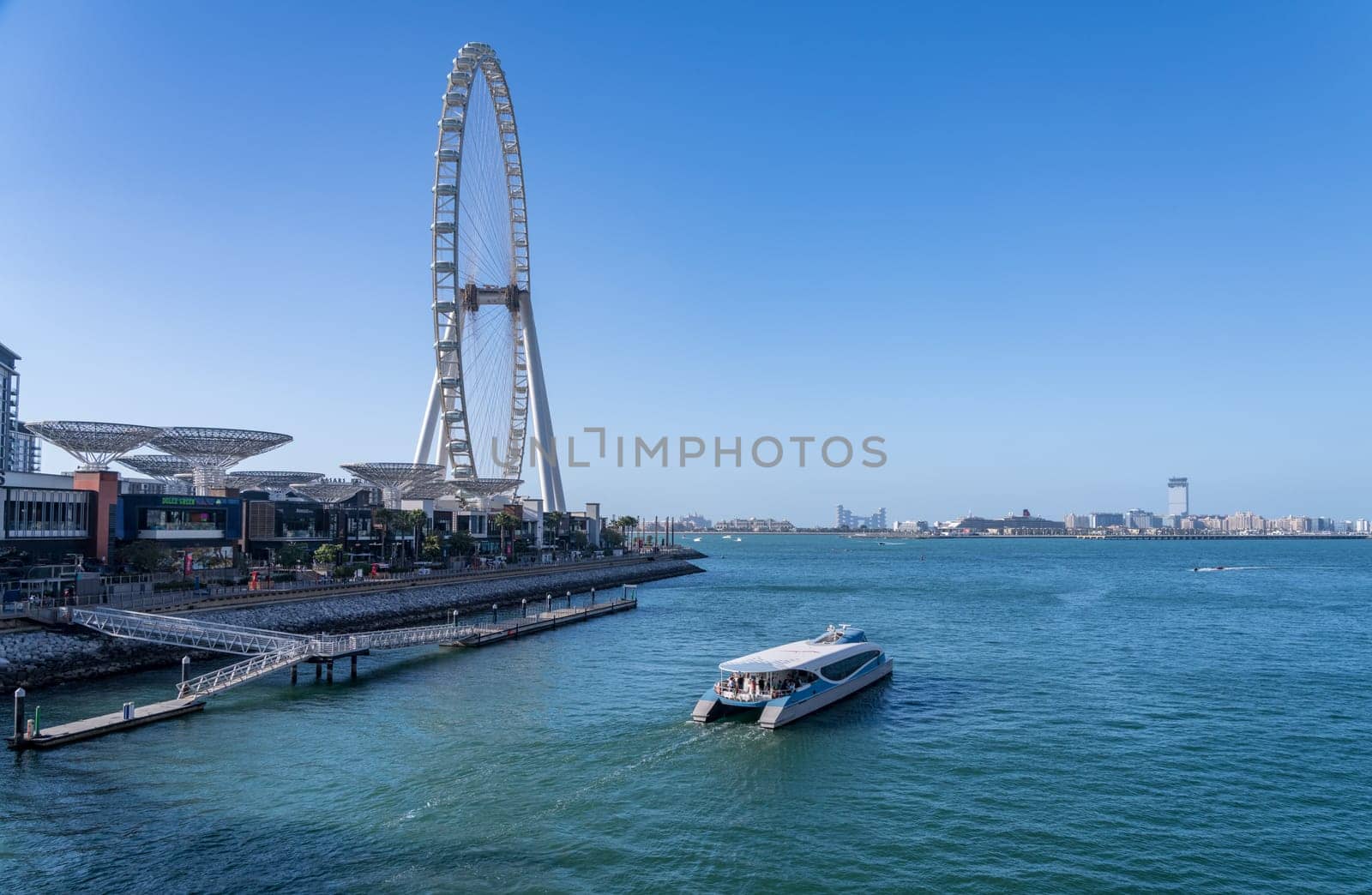 Dubai, UAE - April 3, 2023: Dubai Ferry departs past the Ain Dubai Observation Wheel on BlueWaters Island