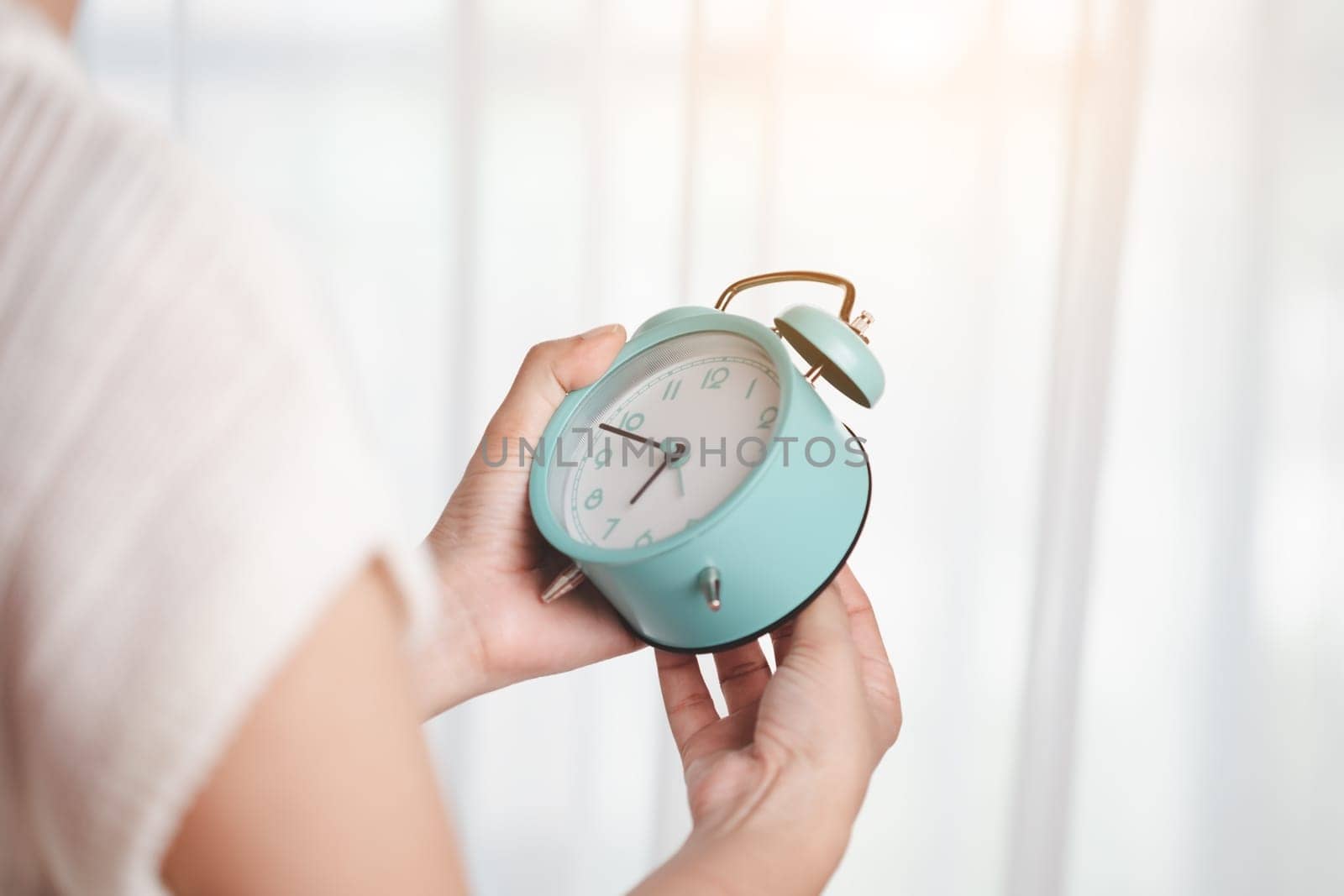 Asian woman's hand setting the time at the clock to set a reminder or set an alarm for time management concept.