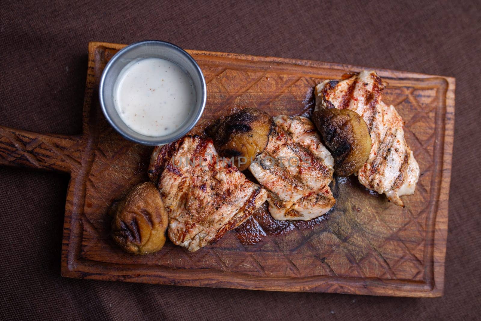 grilled chicken fillet with mushrooms on a wooden board top view.