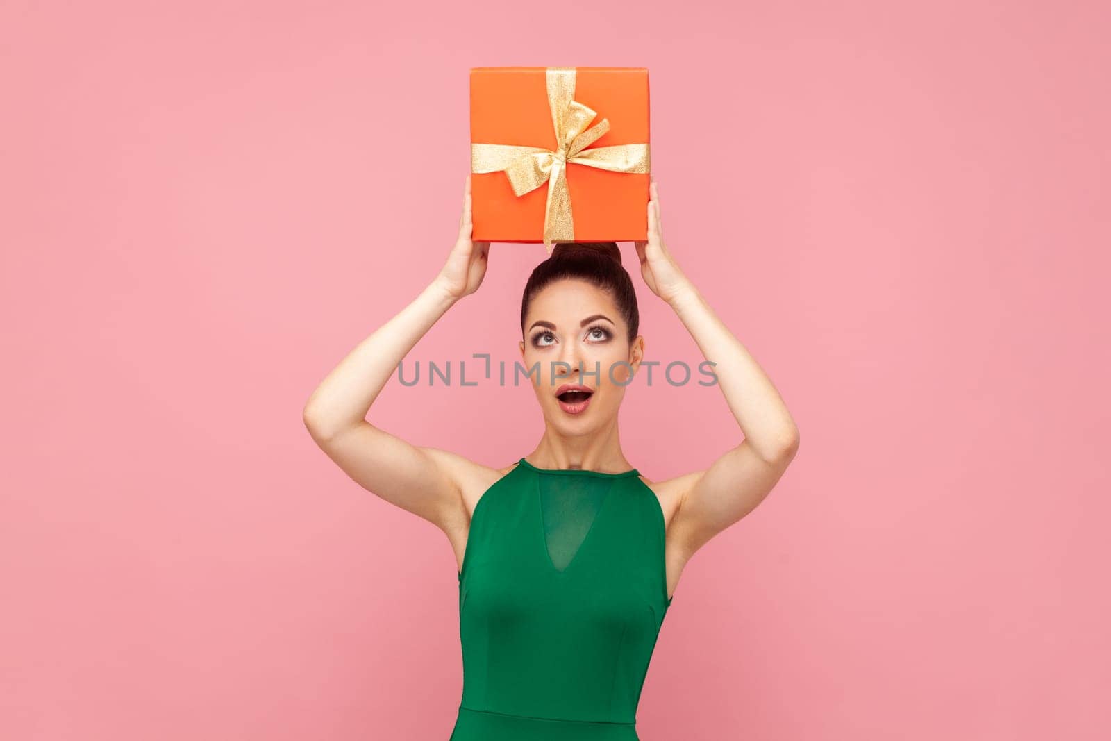 Surprised astonished amazed woman standing holding red present box above her head, being excited. by Khosro1