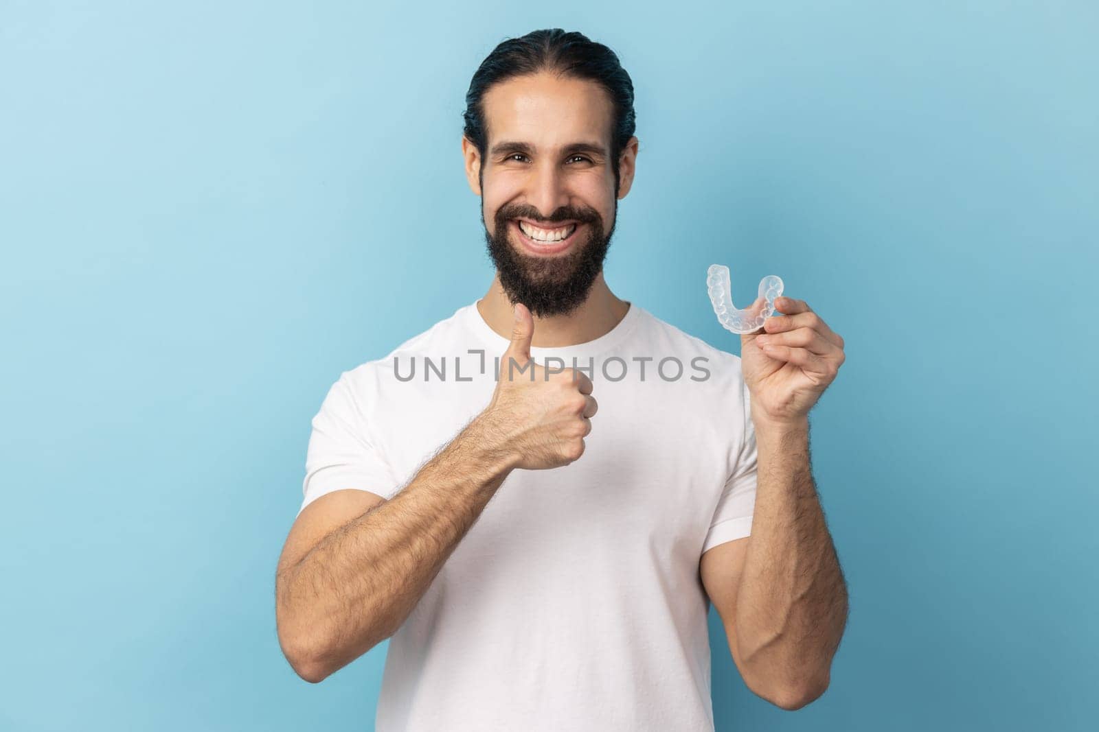 Man holding dental aligner retainer, dental clinic for beautiful teeth, showing thumb up. by Khosro1