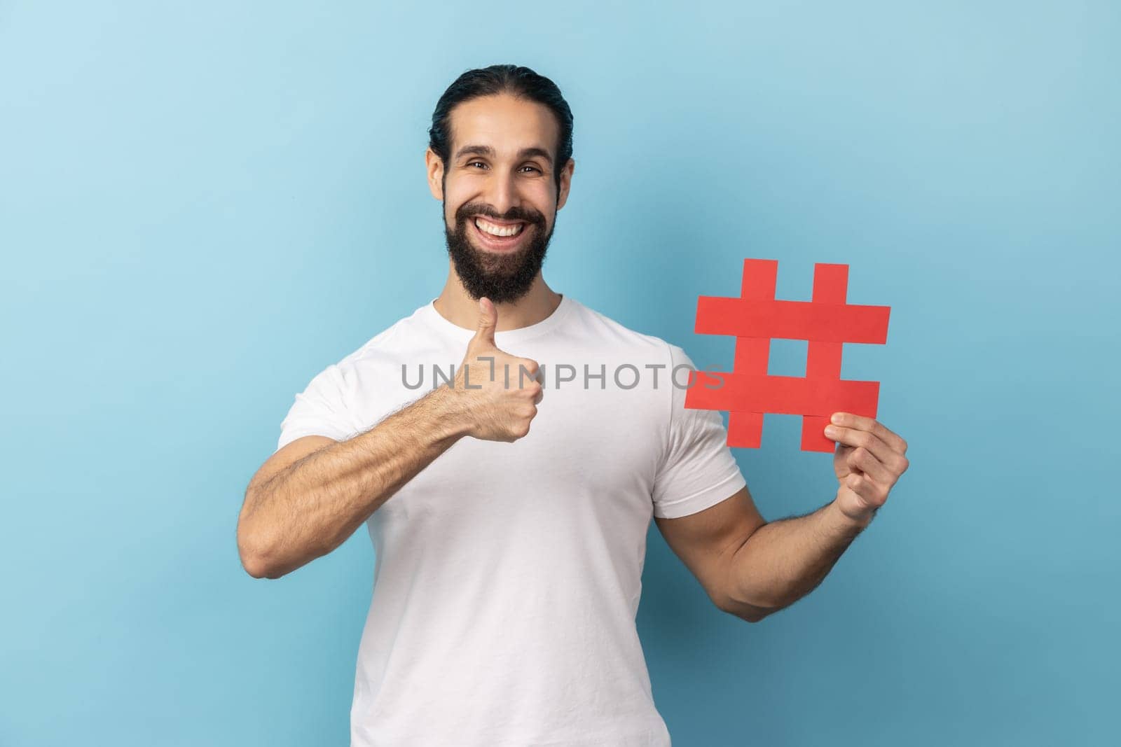 Man holding hashtag symbol, showing thumb up, recommending popular topics, internet trends. by Khosro1