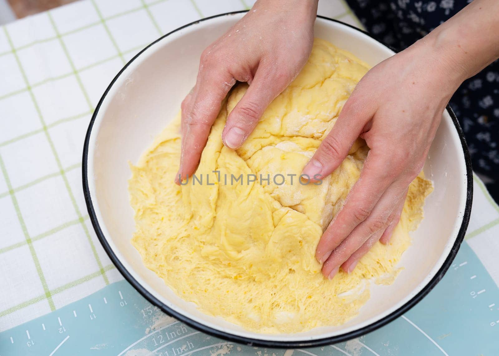 A woman kneads dough with her hands, a baker, baker's hands, dough, hands in flour, handmade baking. View from above