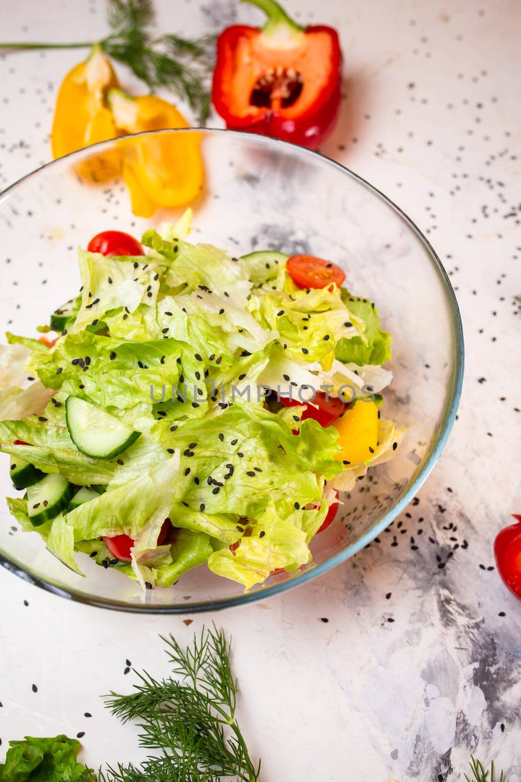 Vegetarian salad with fresh vegetables, lettuce and sesame seeds with tomatoes in a deep glass cup by Pukhovskiy