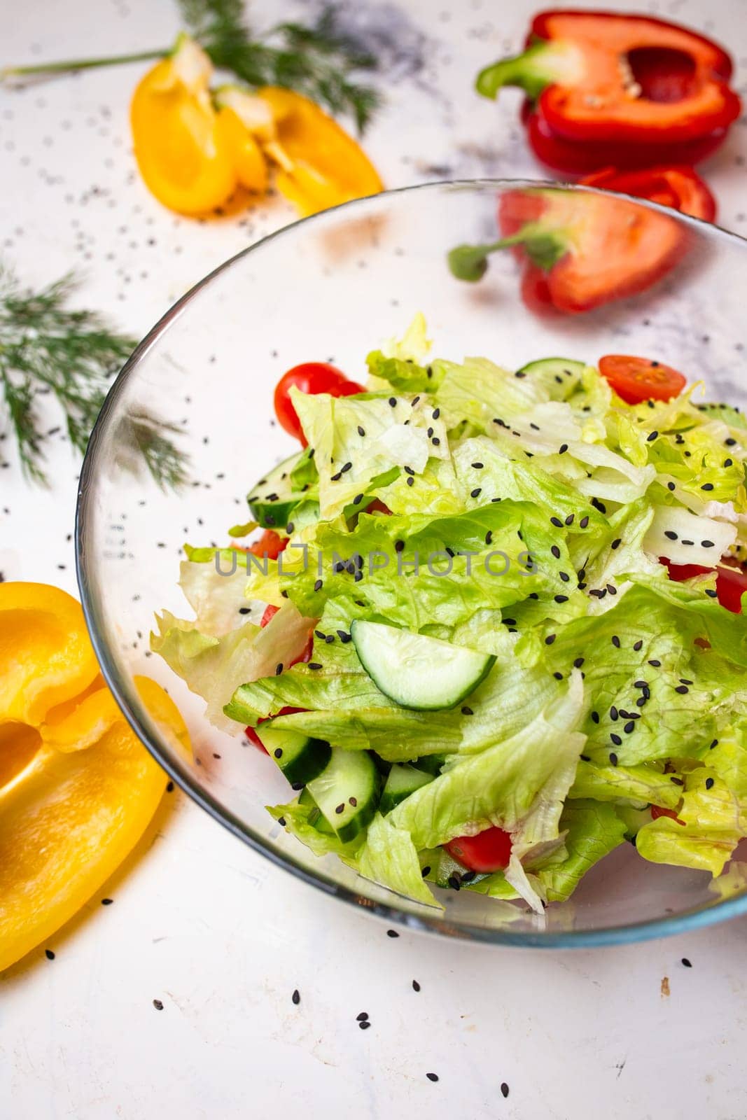 Vegetarian salad with fresh vegetables, lettuce and sesame with tomatoes. Salad in a glass cup top view. by Pukhovskiy