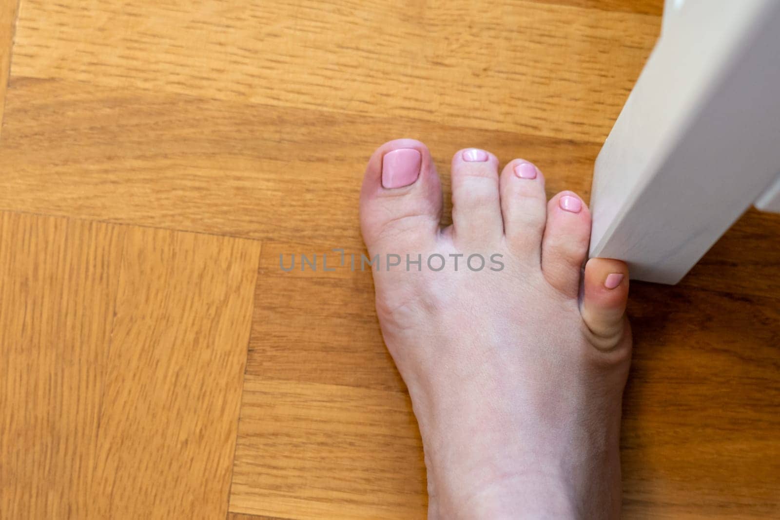Woman hit furniture with the little toe. Accident at home. Injury of foot little finger