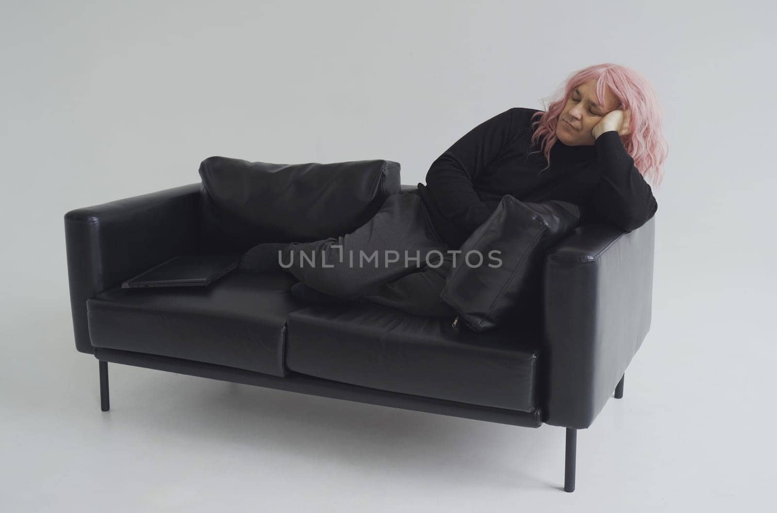 A man in a pink wig is sleeping on the couch. White background.