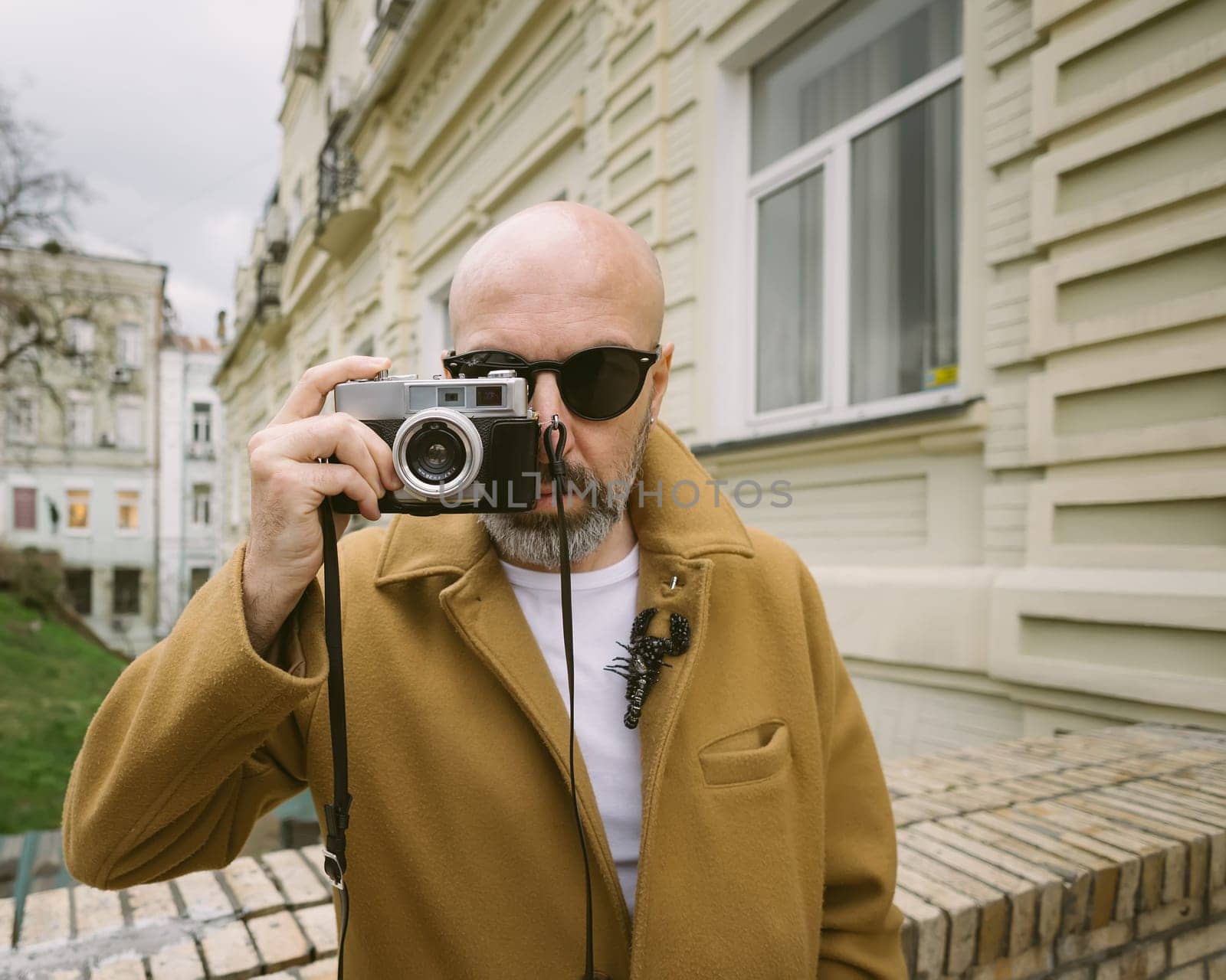 Handsome beard photographer makes pictures on film retro camera in the Kyiv city, Ukraine