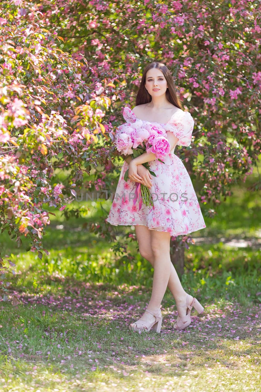 girl, stands with a bouquet of peonies, in garden, in sunny day by Zakharova