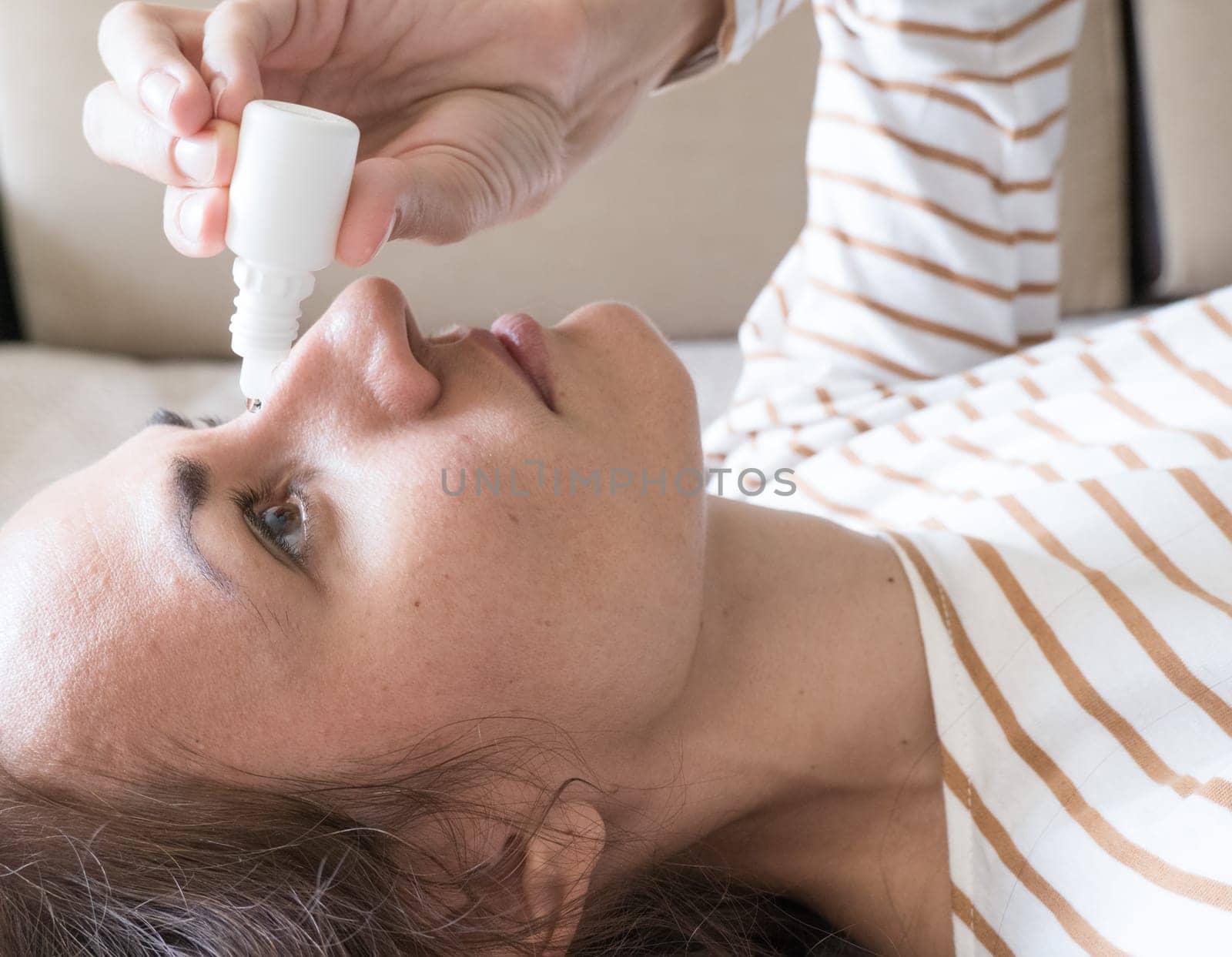 Woman dripping into her eyes with antibacterial drops closeup.