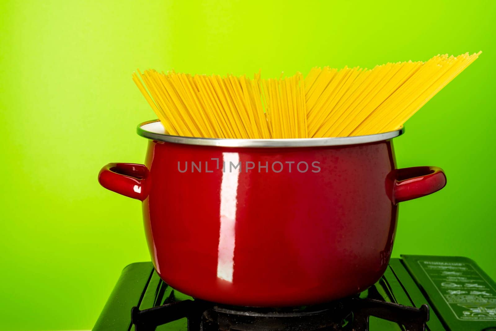 recipe. we cook ourselves. spaghetti in a saucepan. a beautiful red saucepan with spaghetti. cooking spaghetti in a saucepan on a gas stove. homemade Italian-style dinner. kitchen saucepan on a green background
