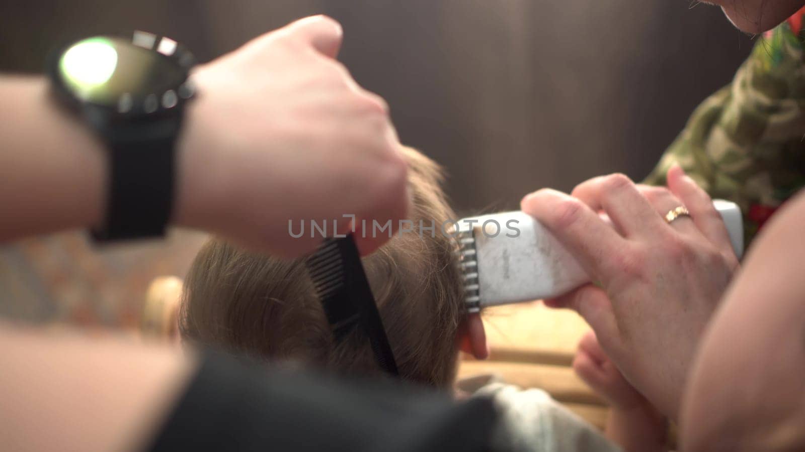 A little boy is getting a haircut from the back of his head with a barber machine. Child at the barbershop. 4k