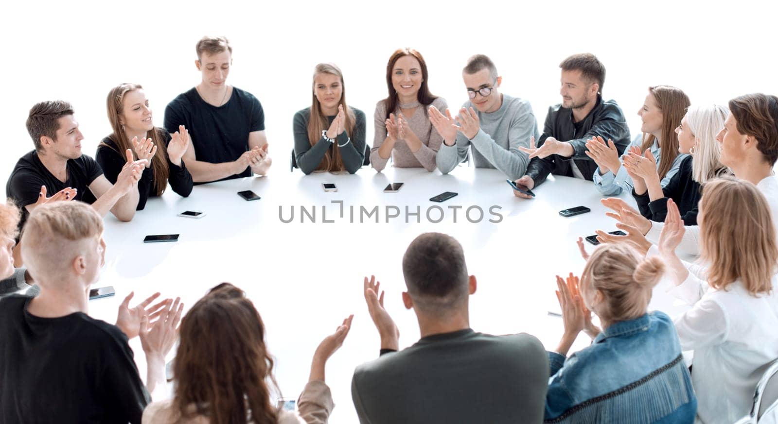 group of young people applauding, sitting at a round table . photo with copy space