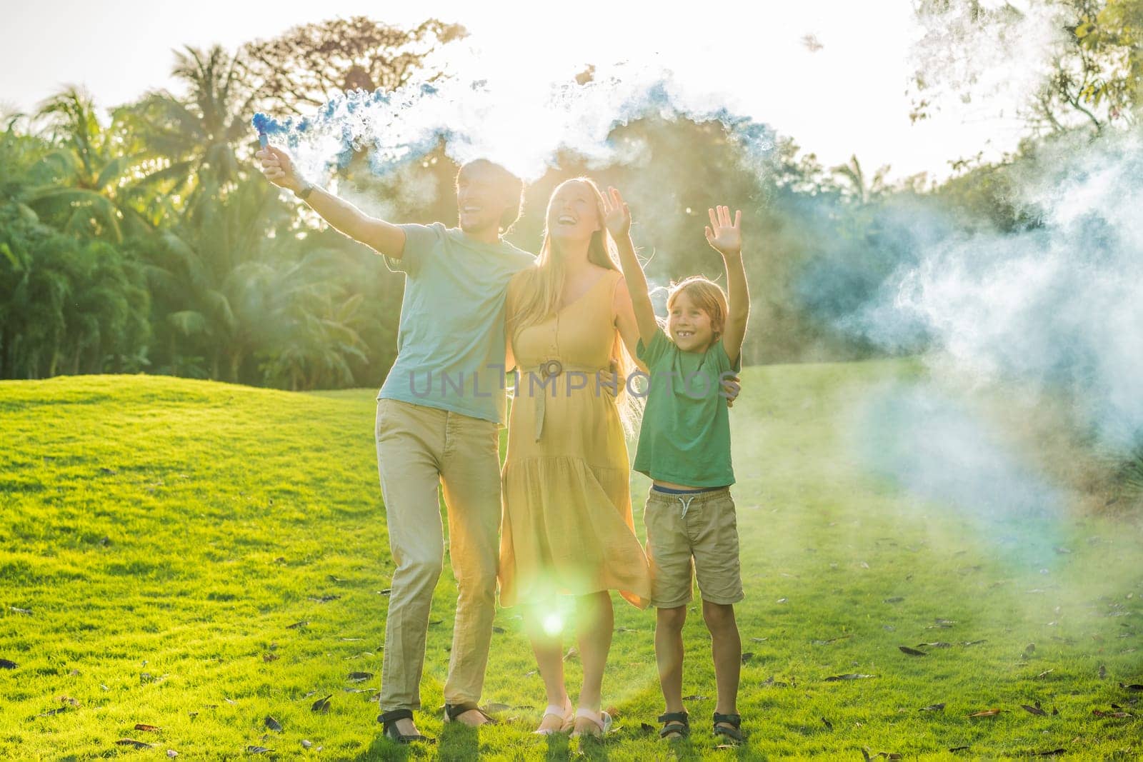Pregnant mom, dad and son at the gender party on the golf course release blue smoke. Gender reveal announcement on the golf course. Loving family expecting baby boy. Happy moments by galitskaya