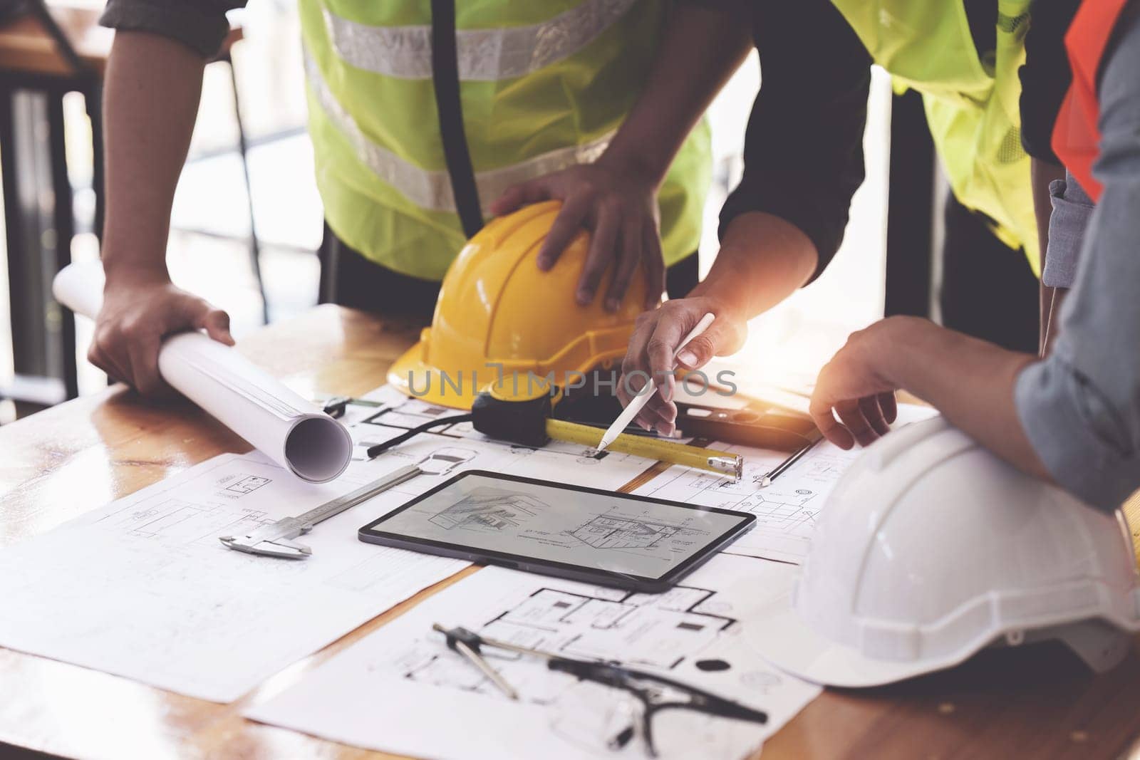 Architect and Engineer working with blueprints for architectural plan, engineer sketching a construction project, green energy concept.