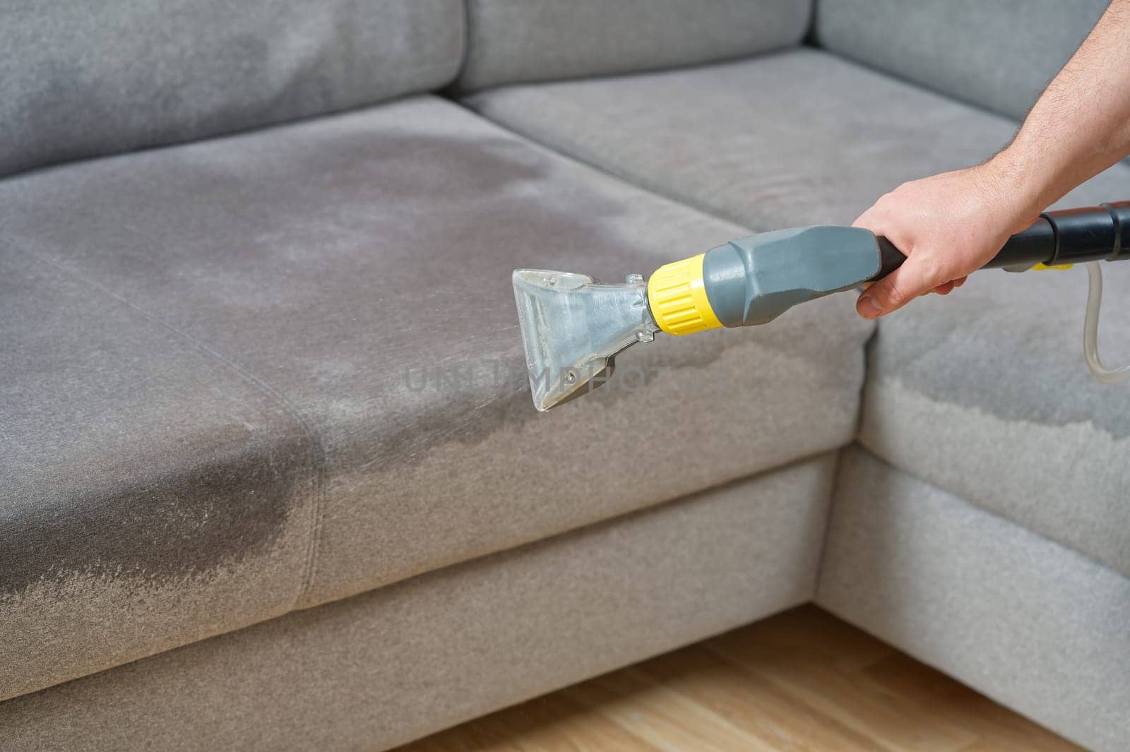 Sofa chemical cleaning with professionally extraction method. Wet textile sofa cleaning. home cleaning service. cleaning sofa with washing suction cleaner closeup.