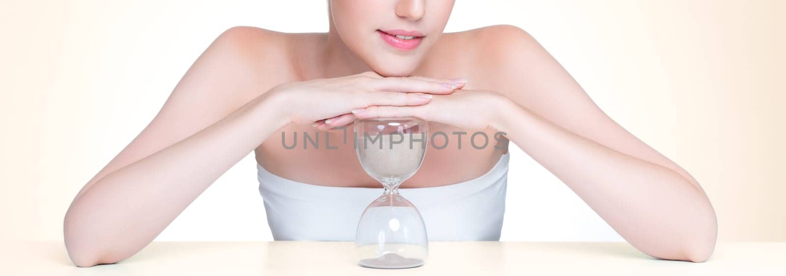 Closeup personable beautiful woman with hourglass as anti-aging skincare concept by biancoblue