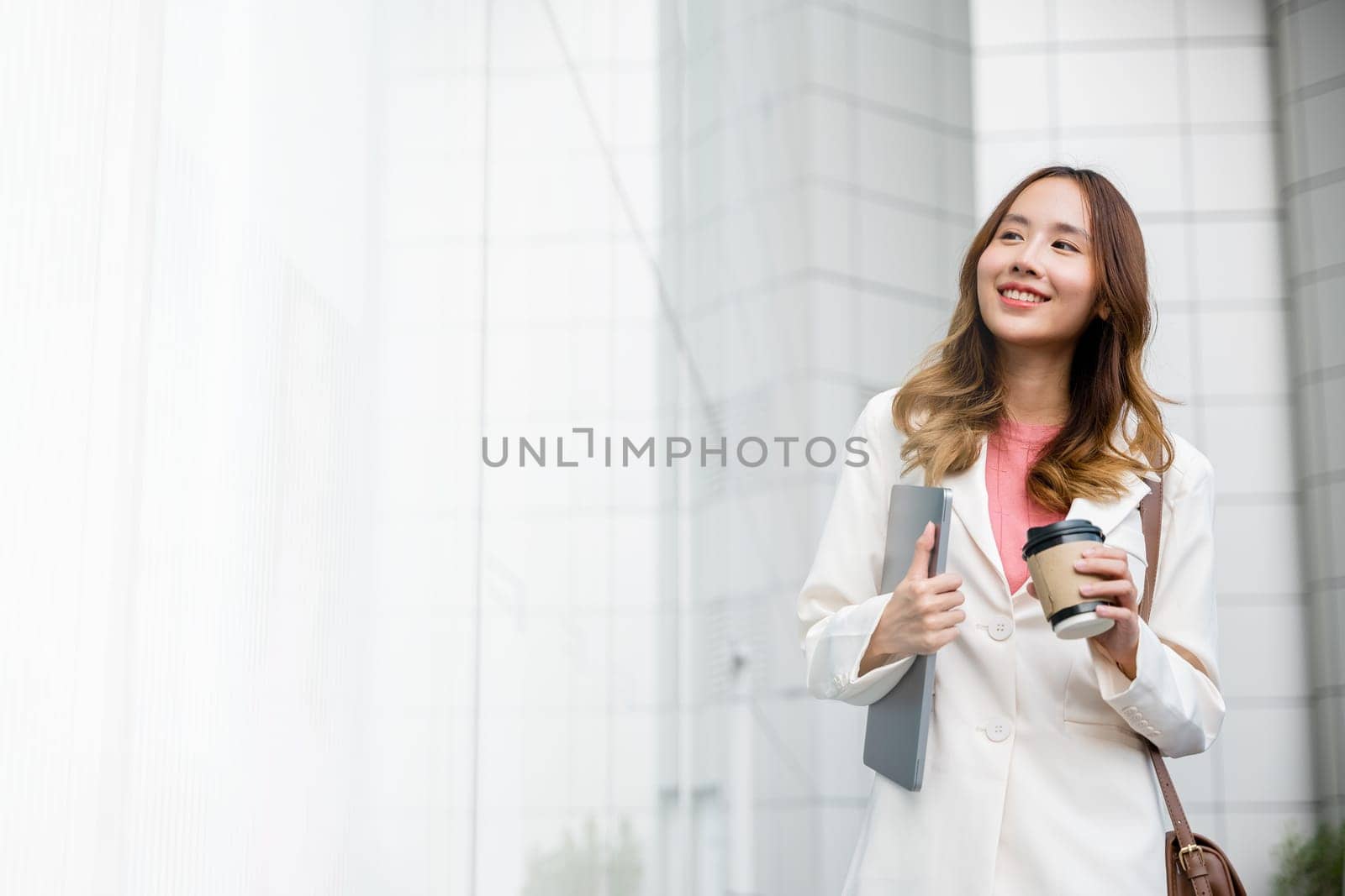 Business woman wearing white suit jacket and smile while go to work outdoor by Sorapop