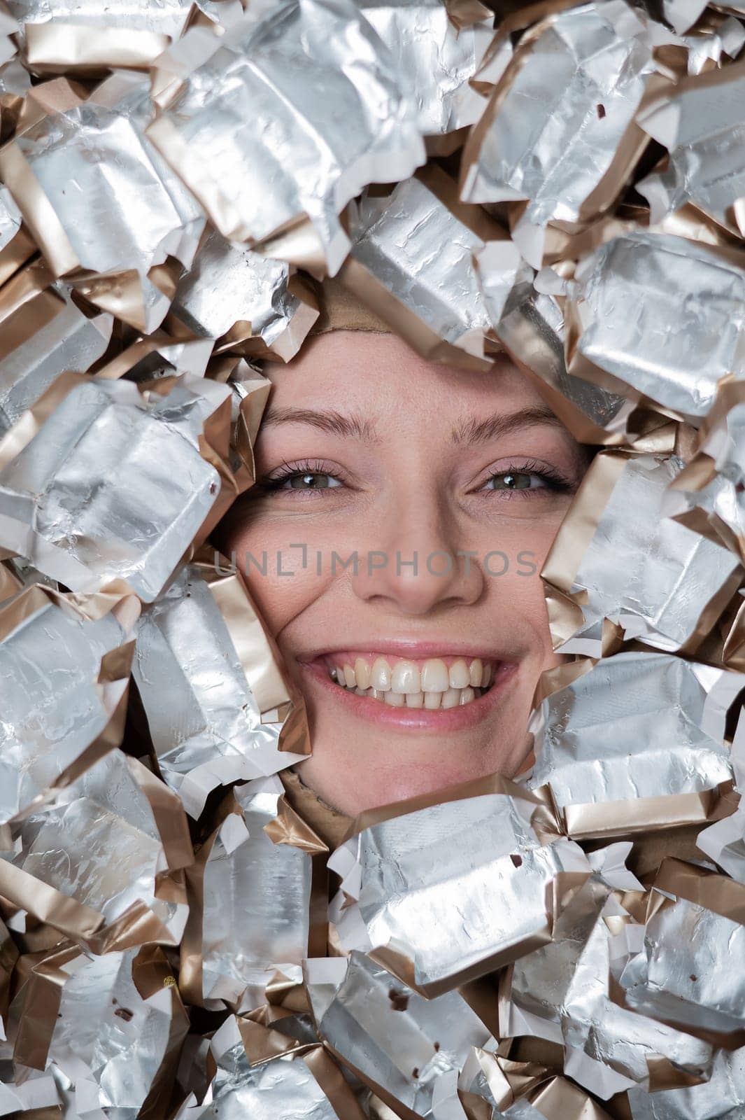 The face of a Caucasian woman surrounded by candy wrappers