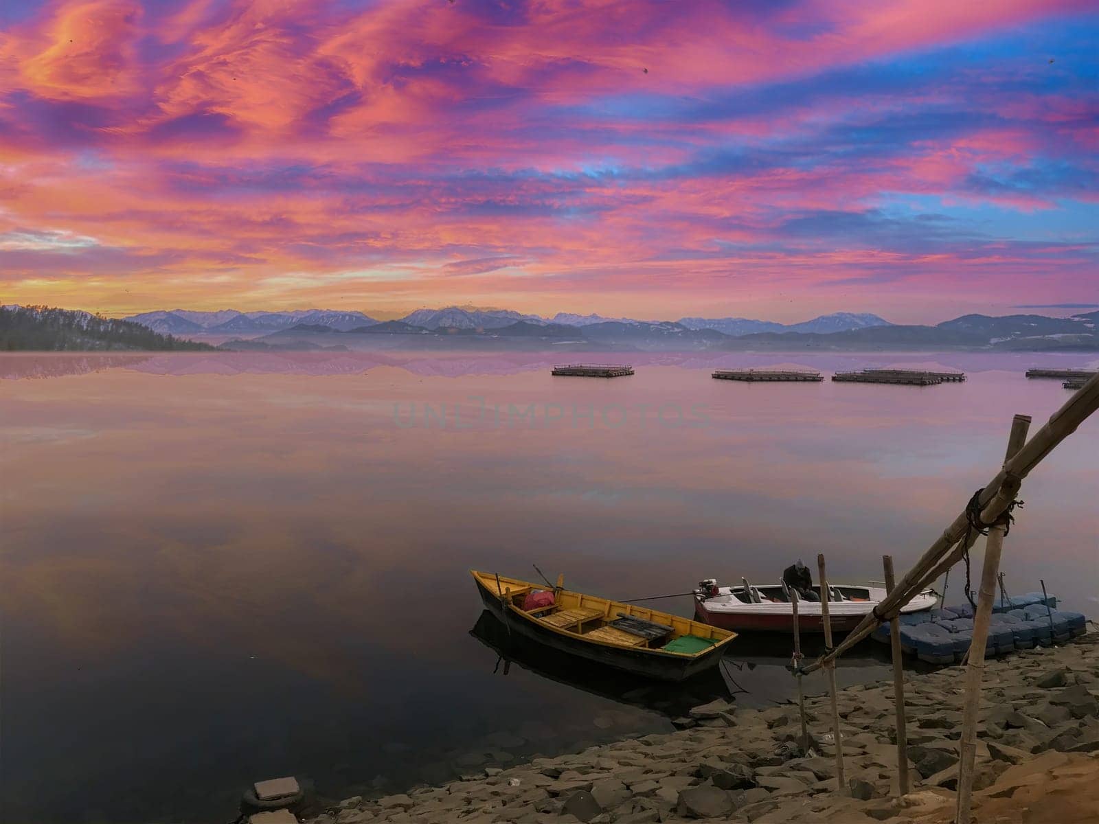 Very beautiful evening view of pink sky in the background with a boat in the foreground. A burst of evening pink light over the horizon with some boats stranded on the side. High-quality photo