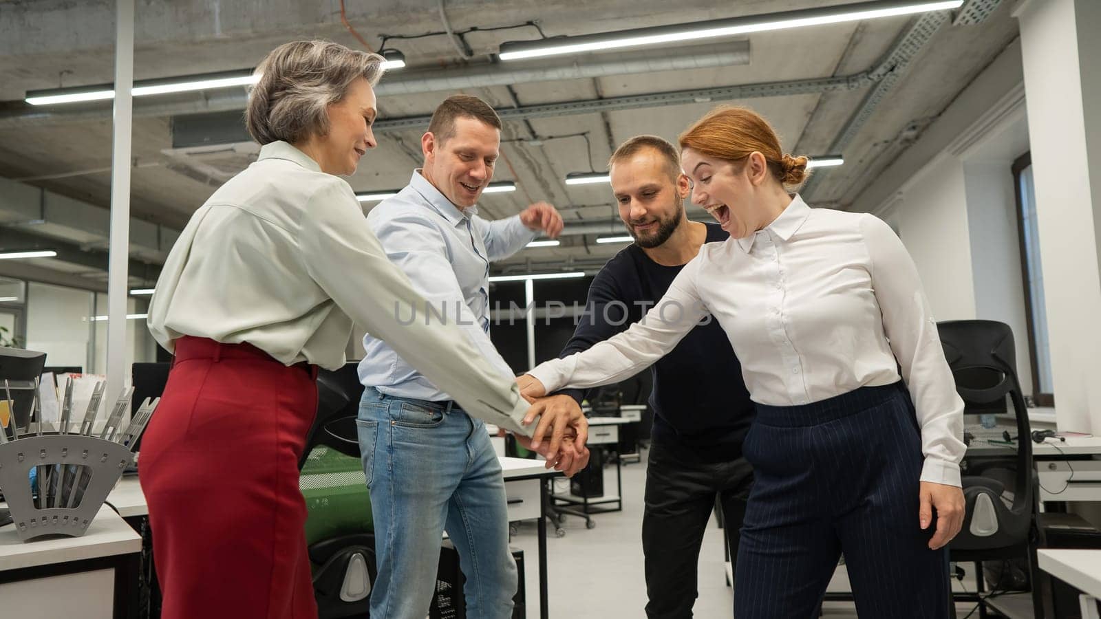 Four colleagues give the low five in the office. by mrwed54