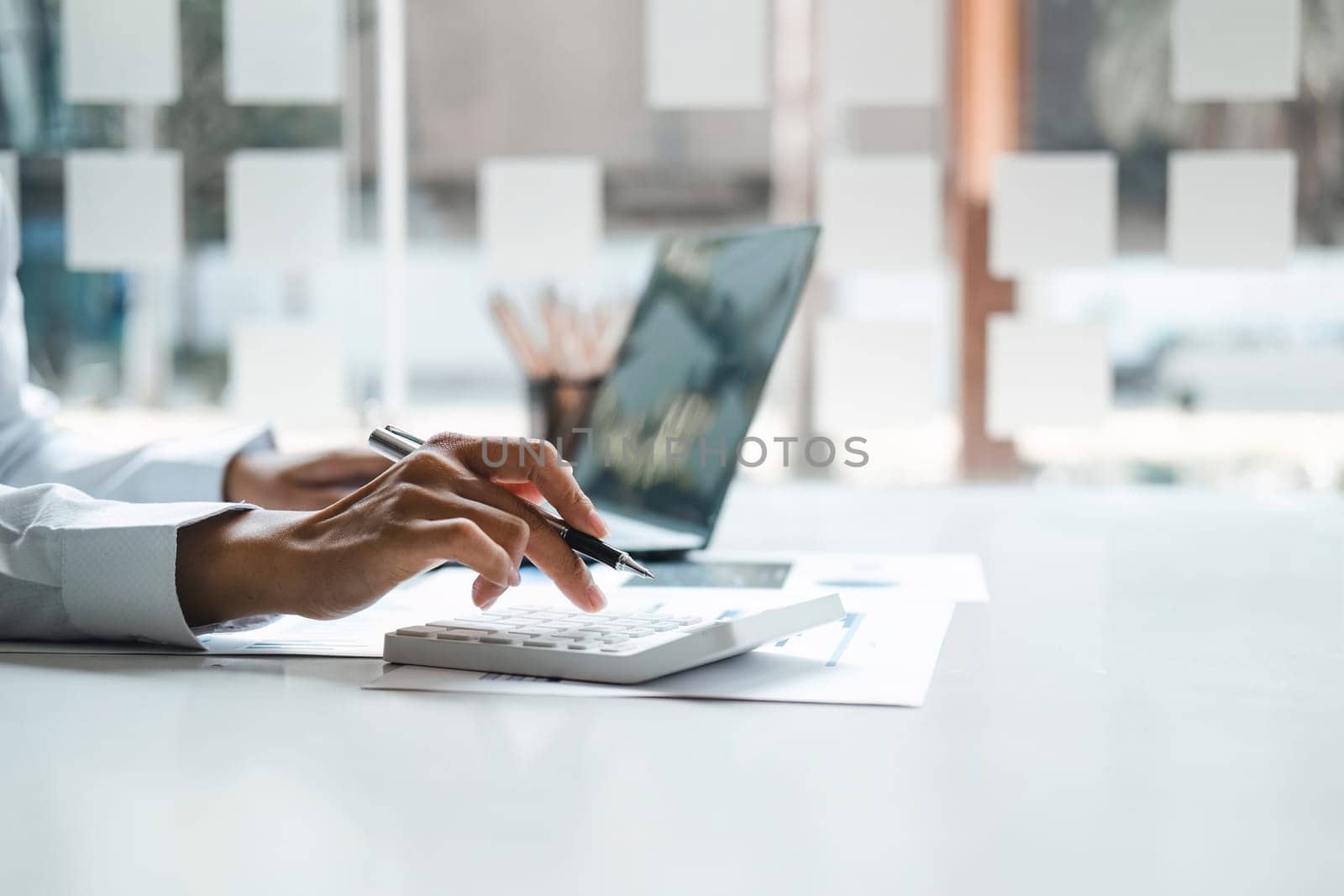 Business woman using calculator for do math finance on wooden desk in office and business working background, tax, accounting, statistics and analytic research concept.