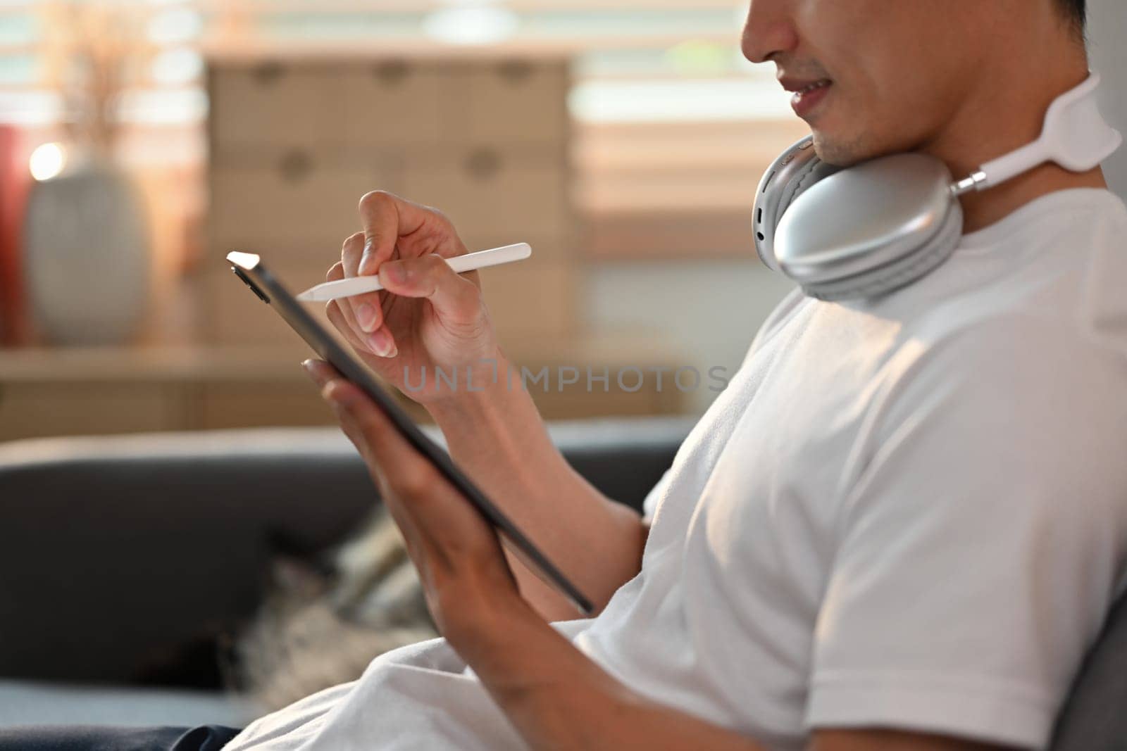 Side view of man in casual clothes using stylus pen writing on digital tablet screen. Communication, technology and lifestyle.