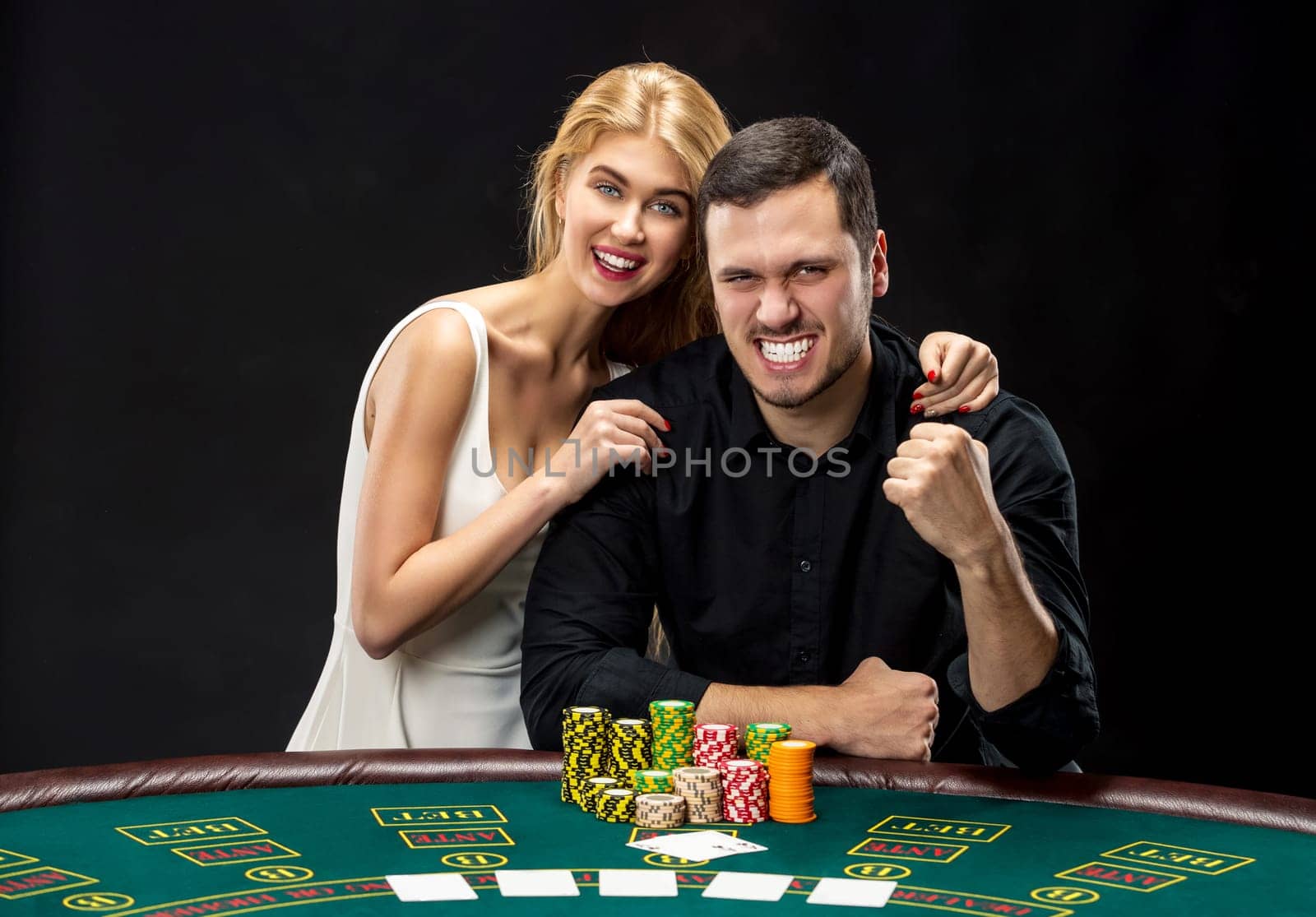 Young couple playing poker and have a good time in casino, woman embracing man.