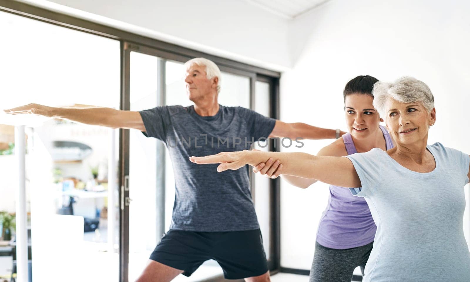 Yoga really does benefit anyone and everyone. an instructor guiding a senior couple in a yoga class