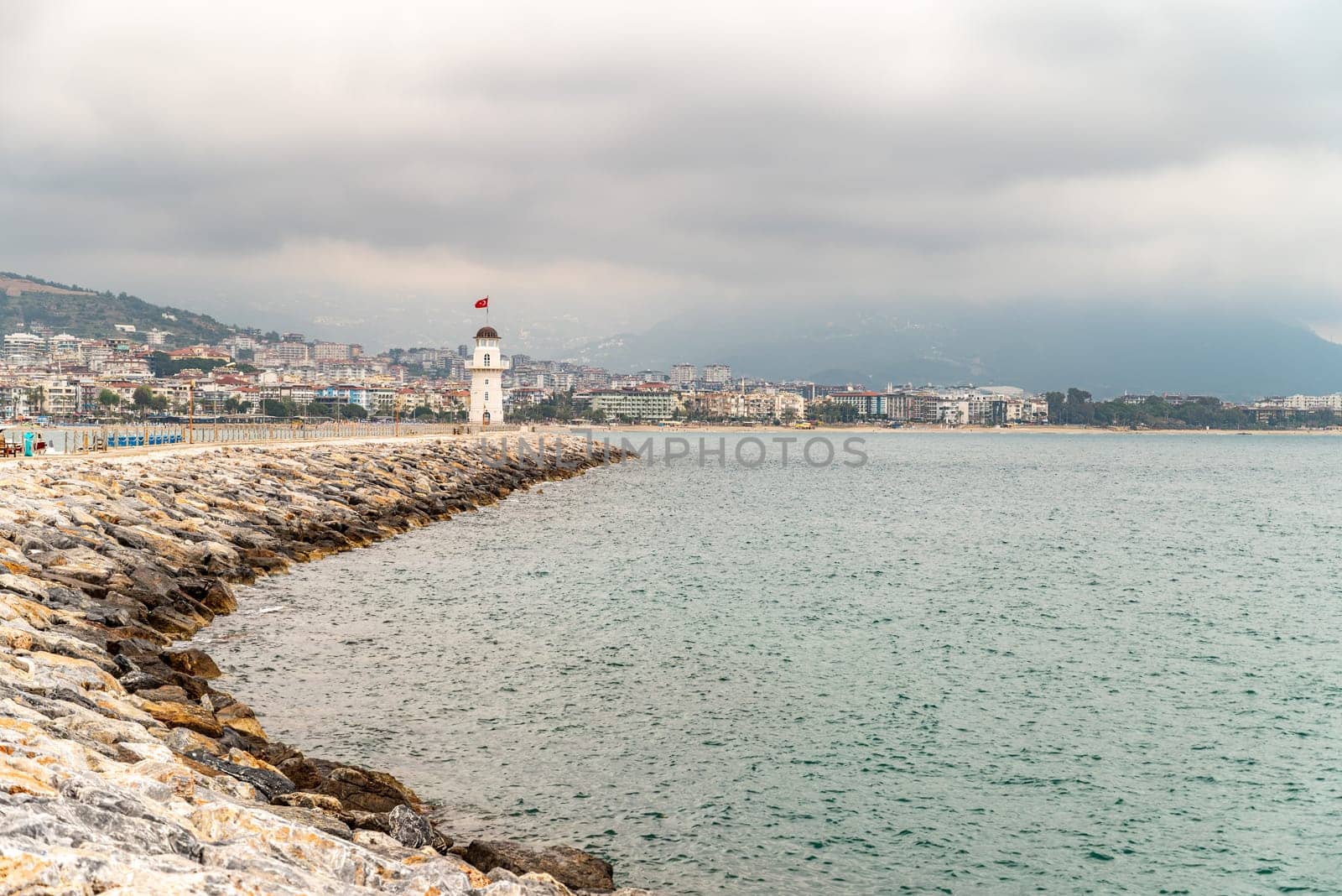 Alanya lighthouse and city view behind it at a cloudy sunset by Sonat