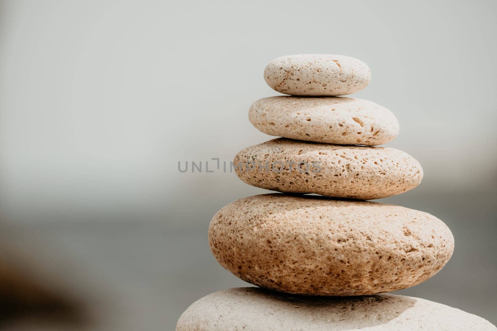 Pyramid stones on the seashore with warm sunset on the sea background. Happy holidays. Pebble beach, calm sea, travel destination. Concept of happy vacation on the sea, meditation, spa, calmness.