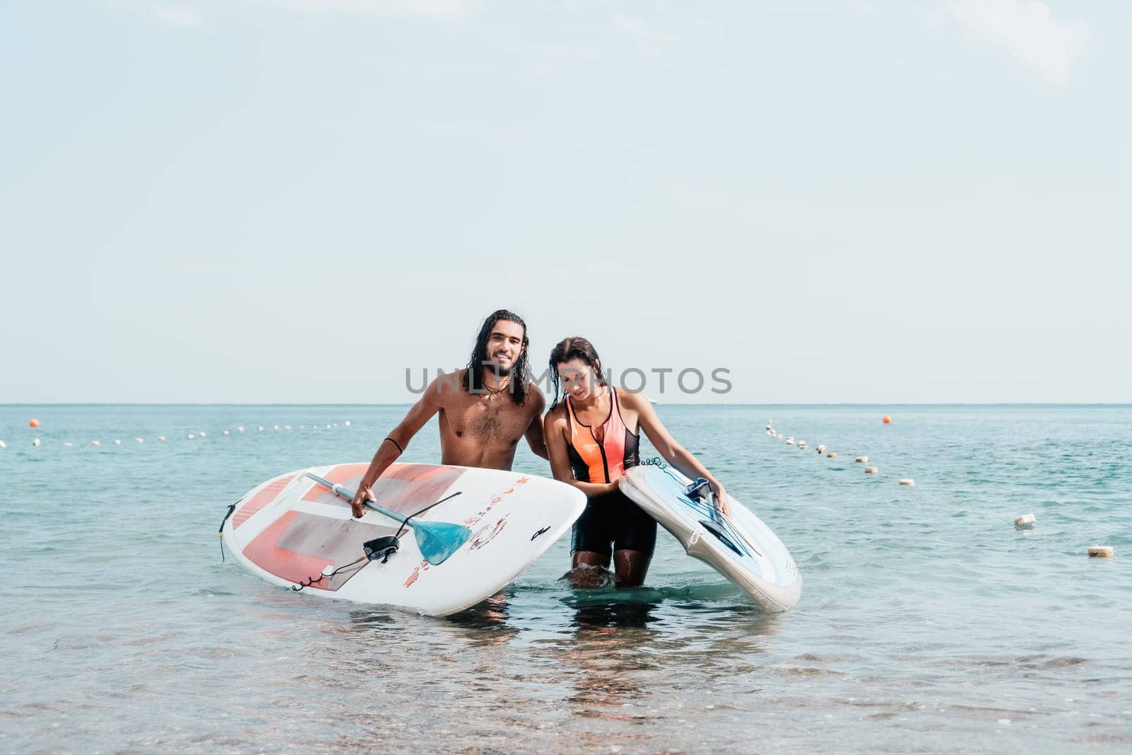 Woman man sea sup. Close up portrait of beautiful young caucasian woman with black hair and freckles looking at camera and smiling. Cute woman portrait in a pink bikini posing on sup board in the sea. by panophotograph