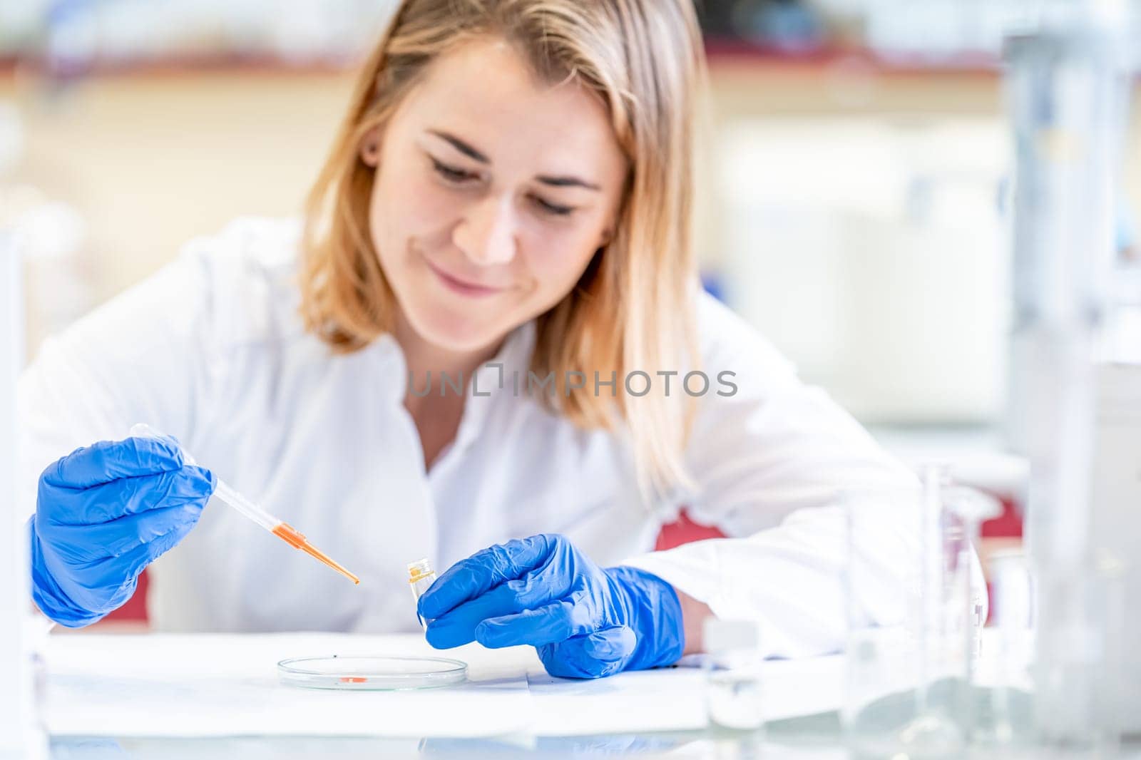 a scientist examines a chemical sample on a peri dish in a laboratory by Edophoto