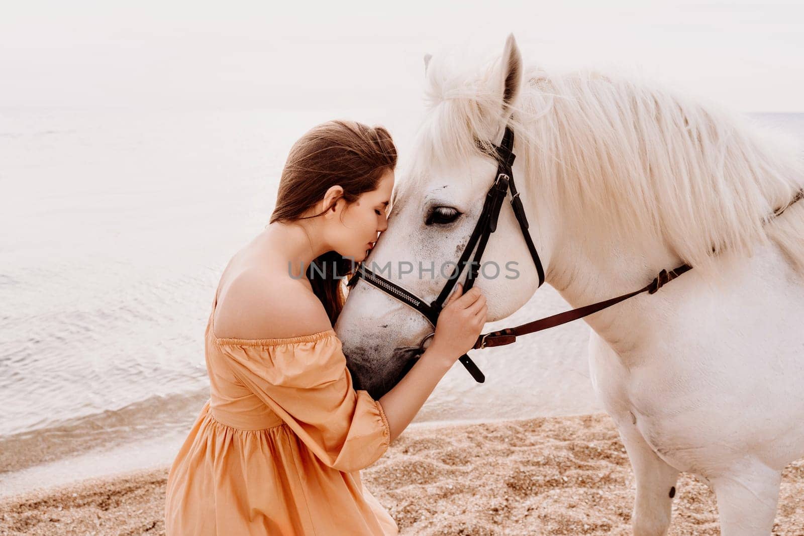 A woman in a dress stands next to a white horse on a beach, with the blue sky and sea in the background. by Matiunina