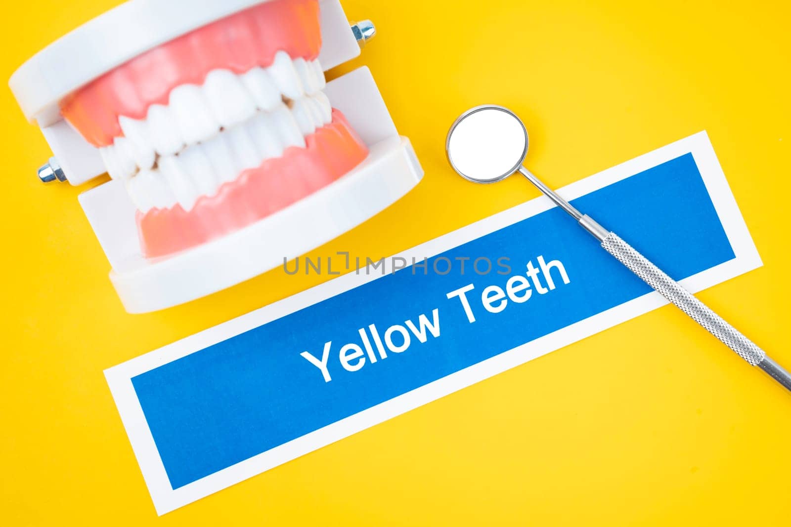 The Dentures model with Yellow teeth dental disease with mirror on yellow background. by Gamjai