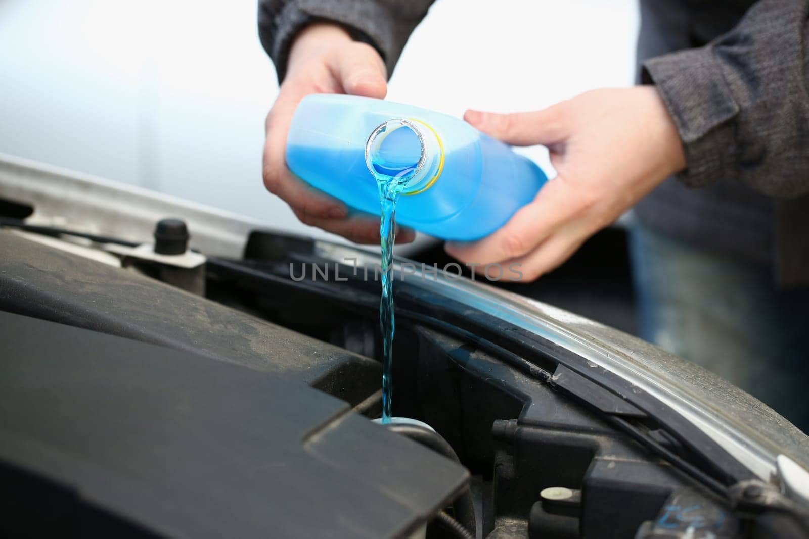 Pouring blue antifreeze liquid for washing car glass. Antifreeze antifreeze and distilled water for car