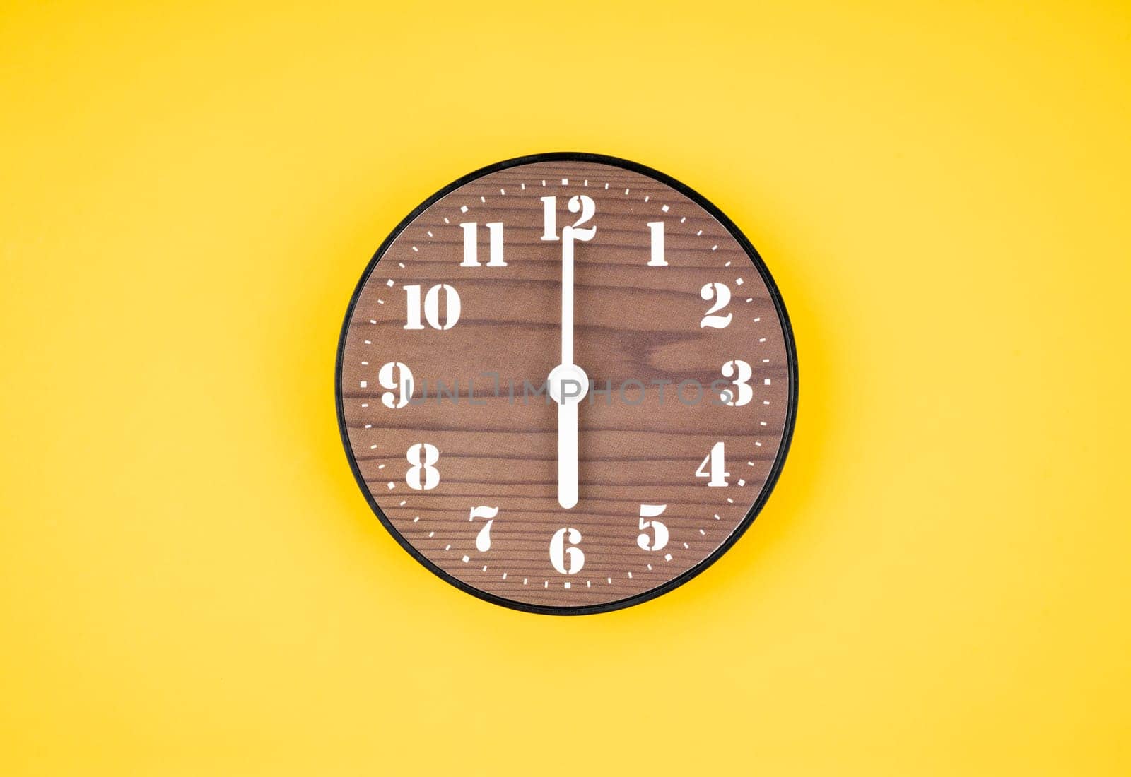 Retro wooden clock at 6 O' clock on yellow color background.