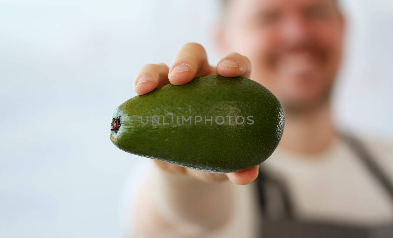 Cook holds fresh juicy green avocado in hands. Natural fresh organic exotic fruits and healthy food