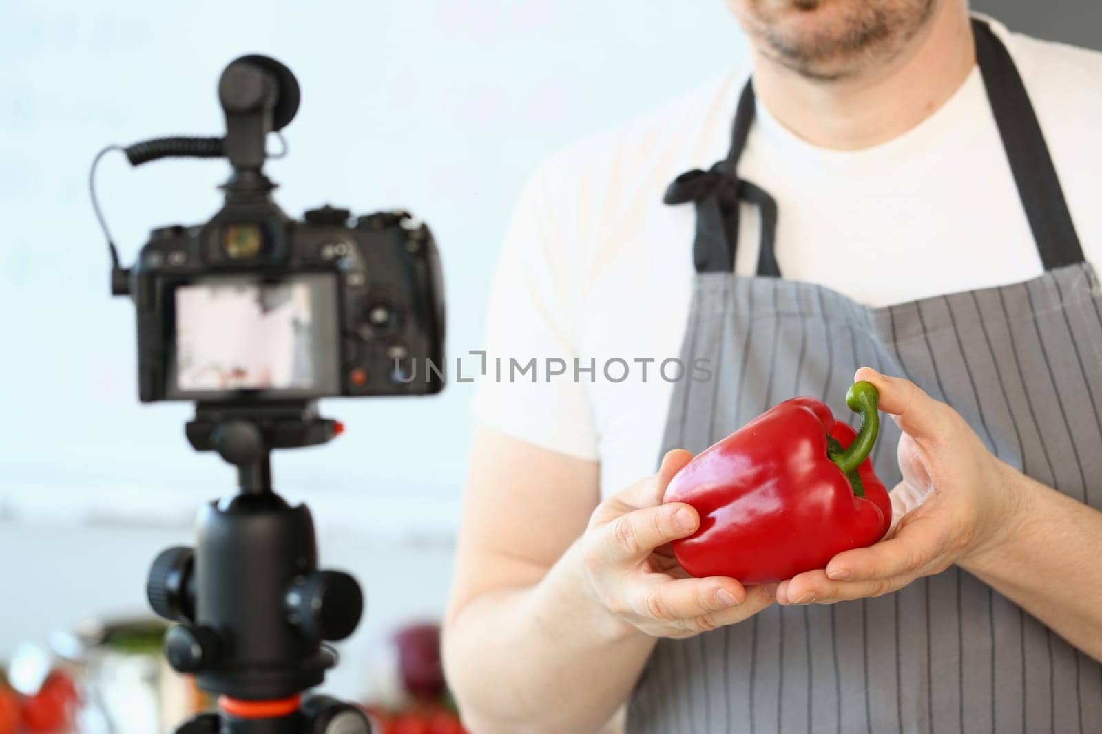 Food blogger creates healthy nutrition and diet content. Man cook holds red in hands and shoots video on camera